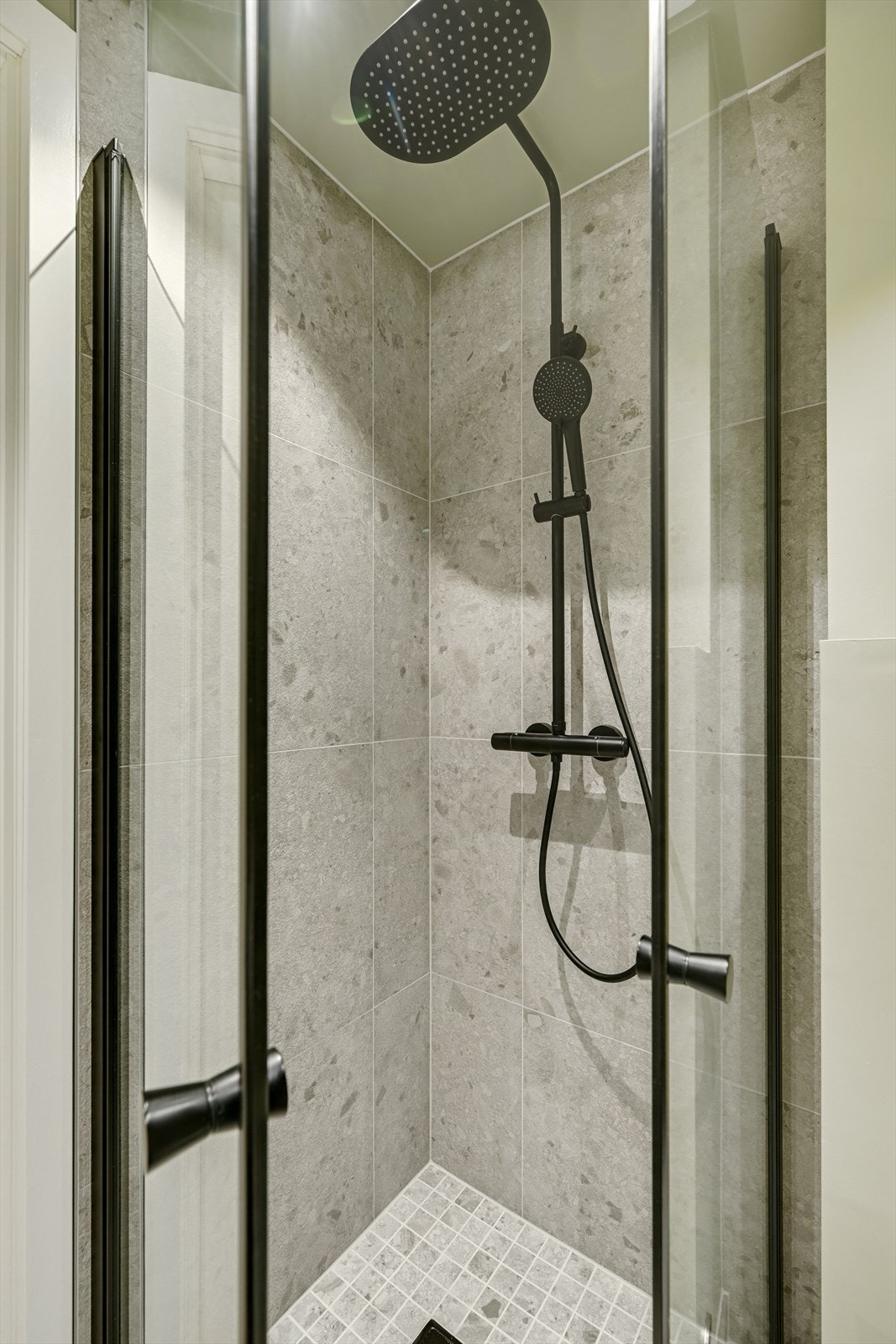 Fliser på vegg i dusj sonen, vegghengt dusj, og glassdører. Galleribilde