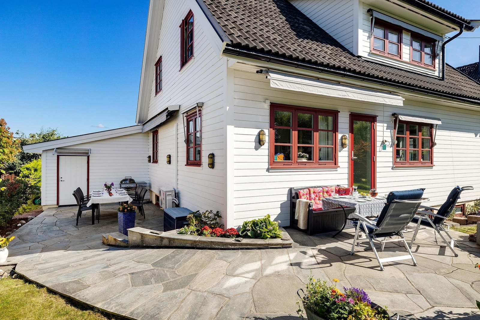 Stor markterrasse med skiferplatting som strekker seg rundt boligen. Galleribilde