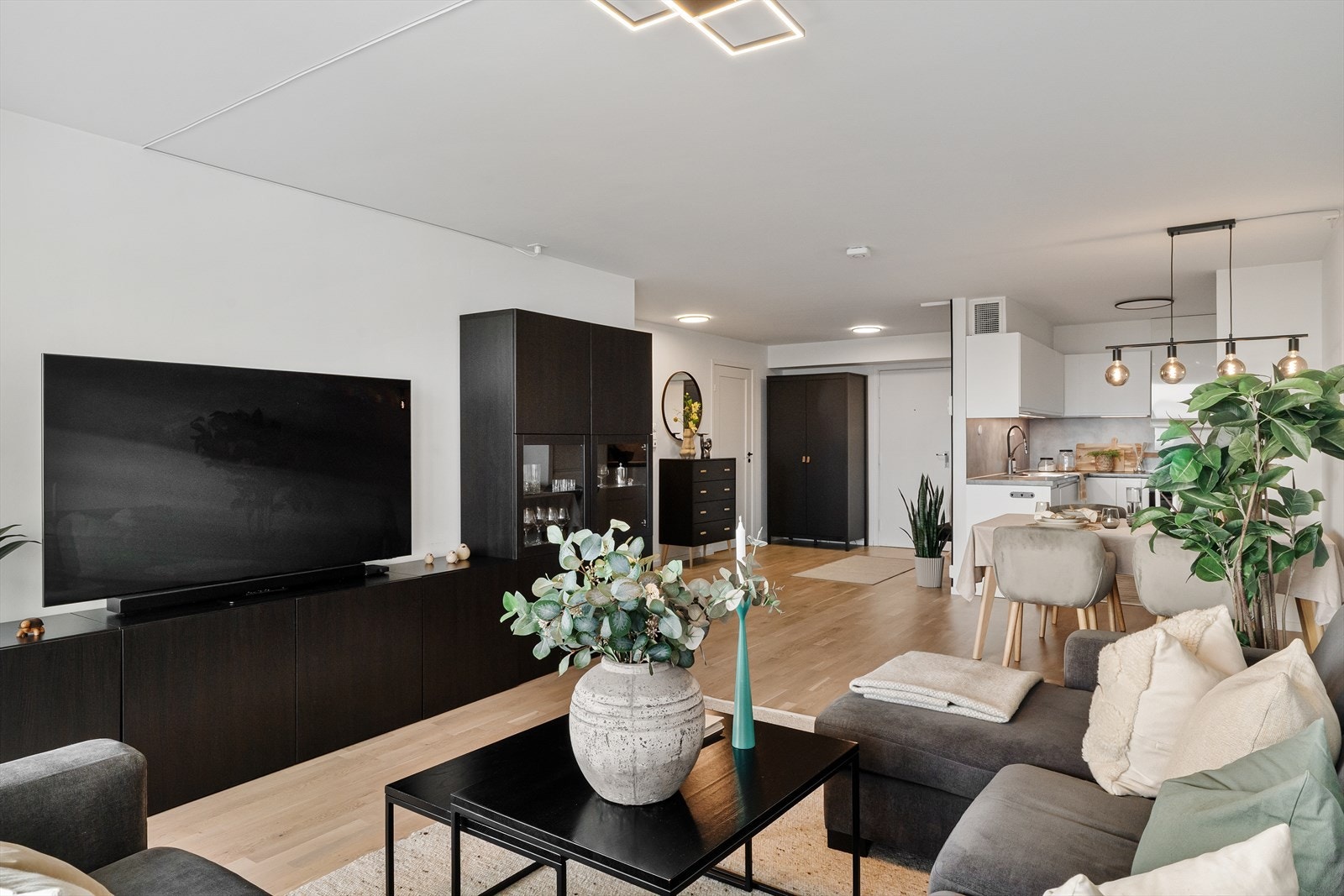 Stue i åpen løsning mot kjøkkenet med god plass til både sofagruppe og stort spisebord Galleribilde