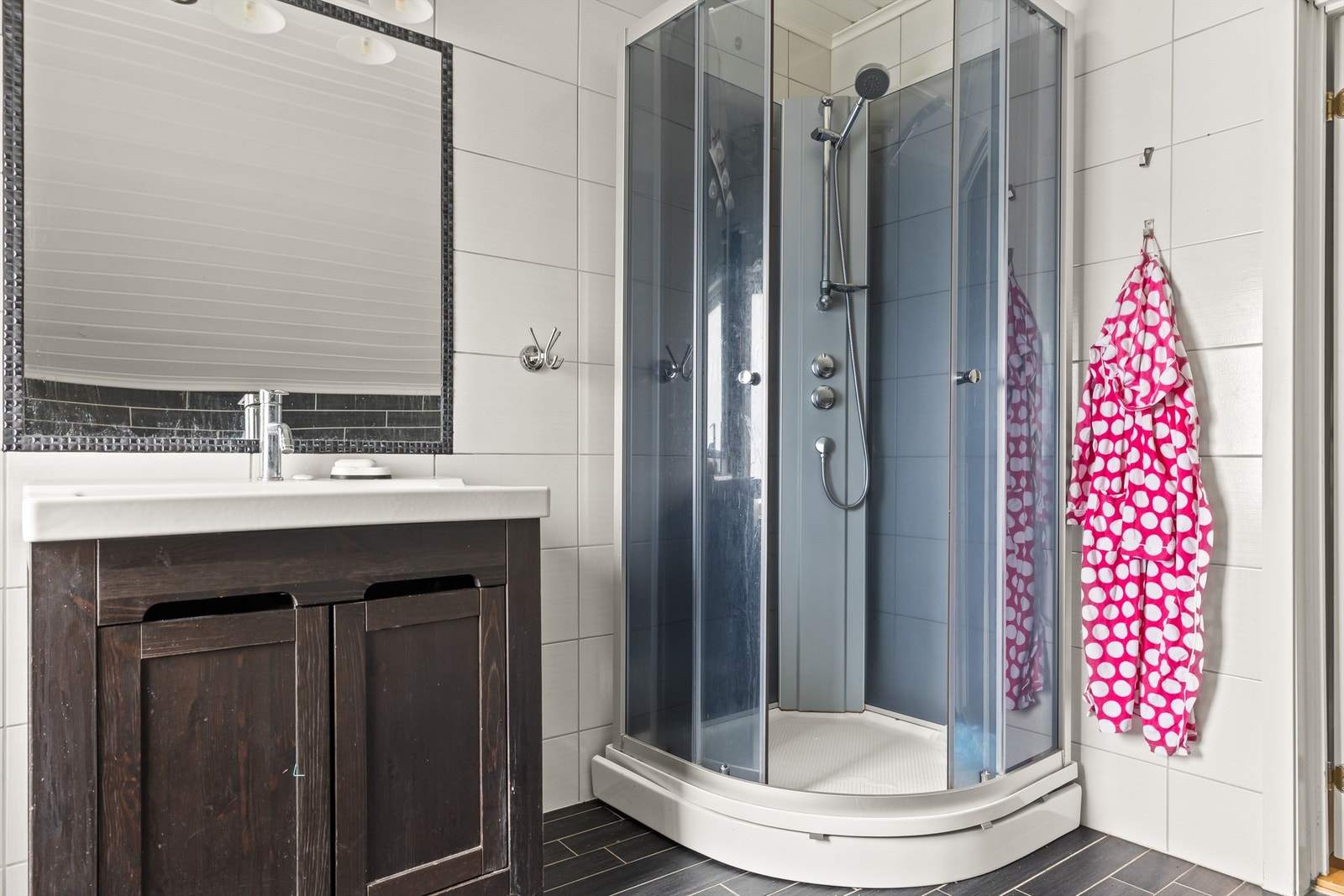 Flislagt bad med dusjkabinett, servant med underskap og speil med belysning. Galleribilde