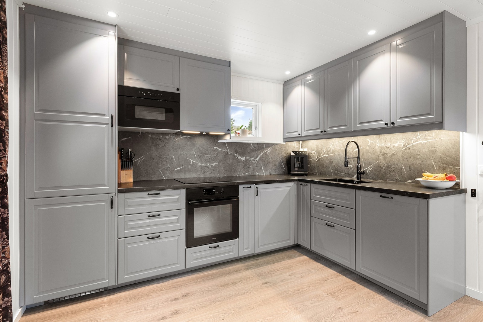 Kjøkkenet har god skapplass, integrert ovn og mikro, samt decorplate på vegg over laminat benkeplate Galleribilde