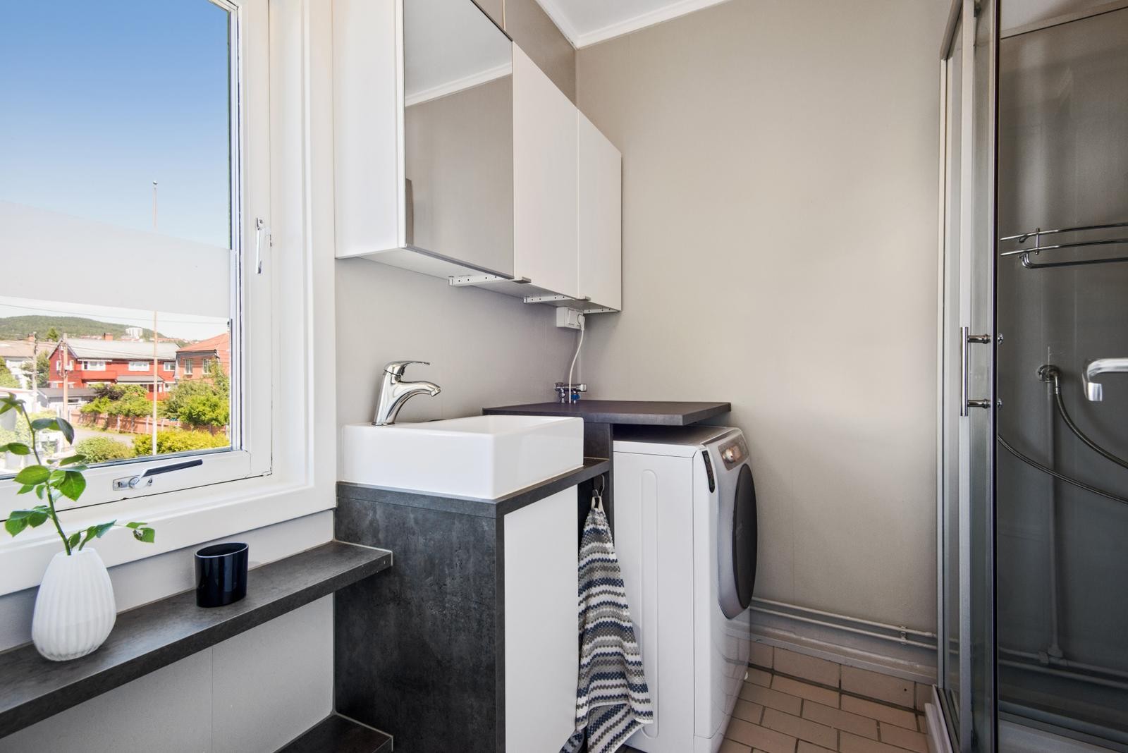 Baderom med kombi vaskemaskin/tørketrommel og dusjkabinett. Galleribilde