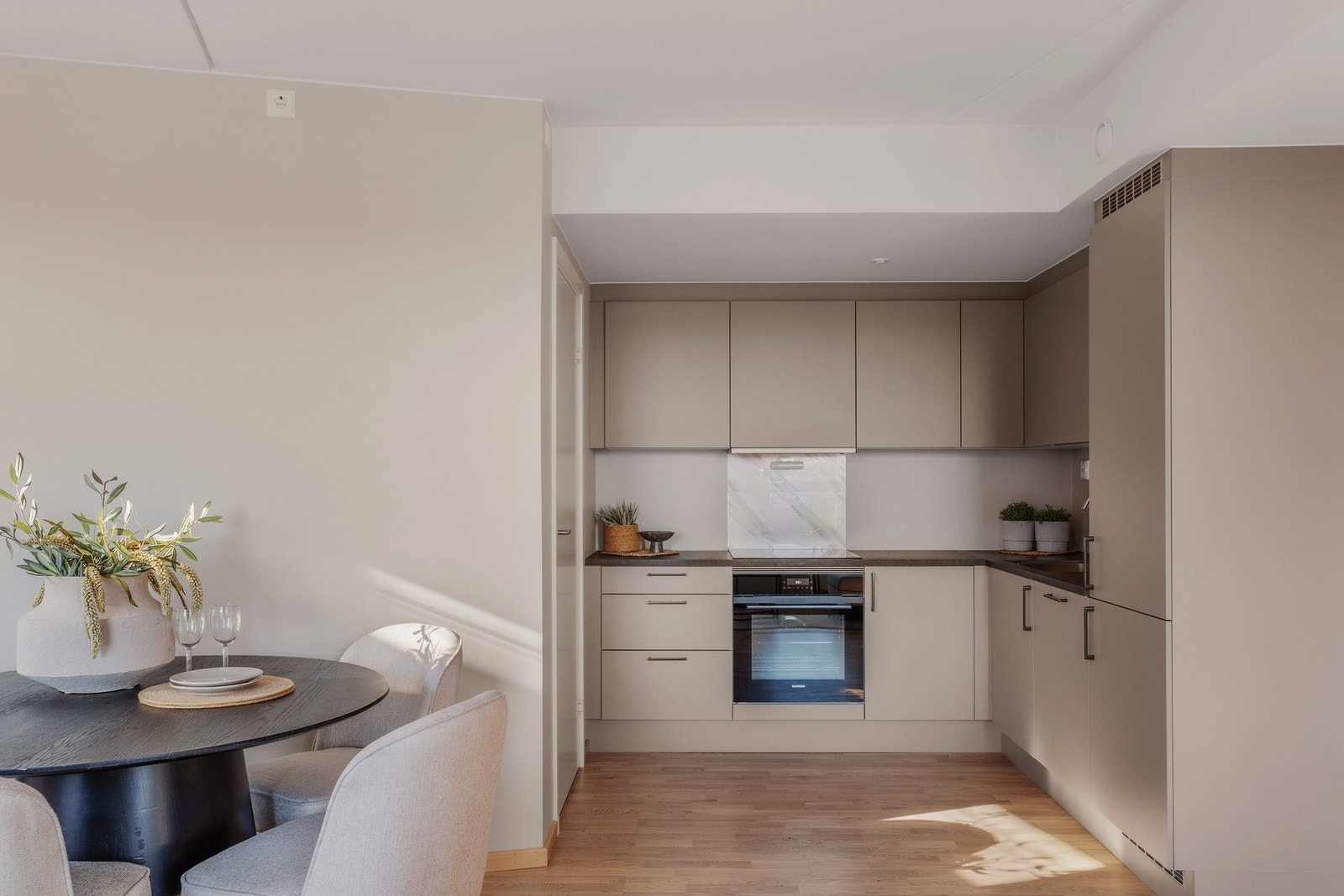 I en åpen løsning mot stuen finner du et stilrent, delikat HTH kjøkken med glatte fronter og benkeplate i laminat. Galleribilde