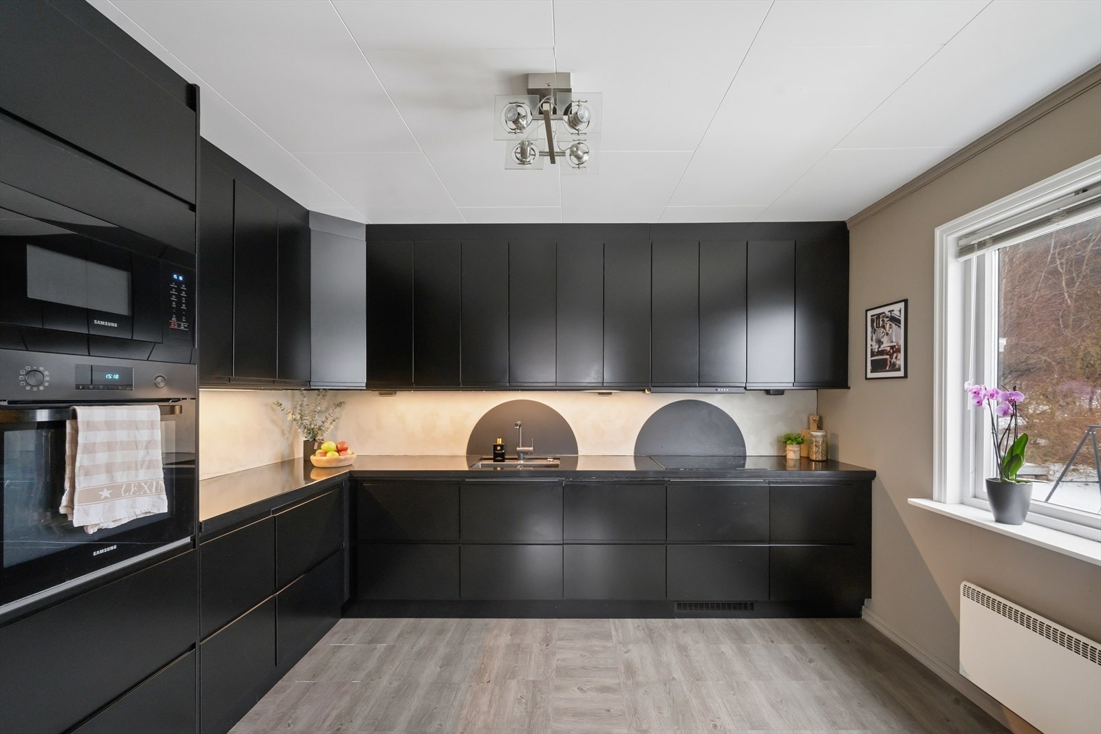 Stilfullt kjøkken med en moderne innredning med glatte fronter og en solid benkeplate i stein. Galleribilde