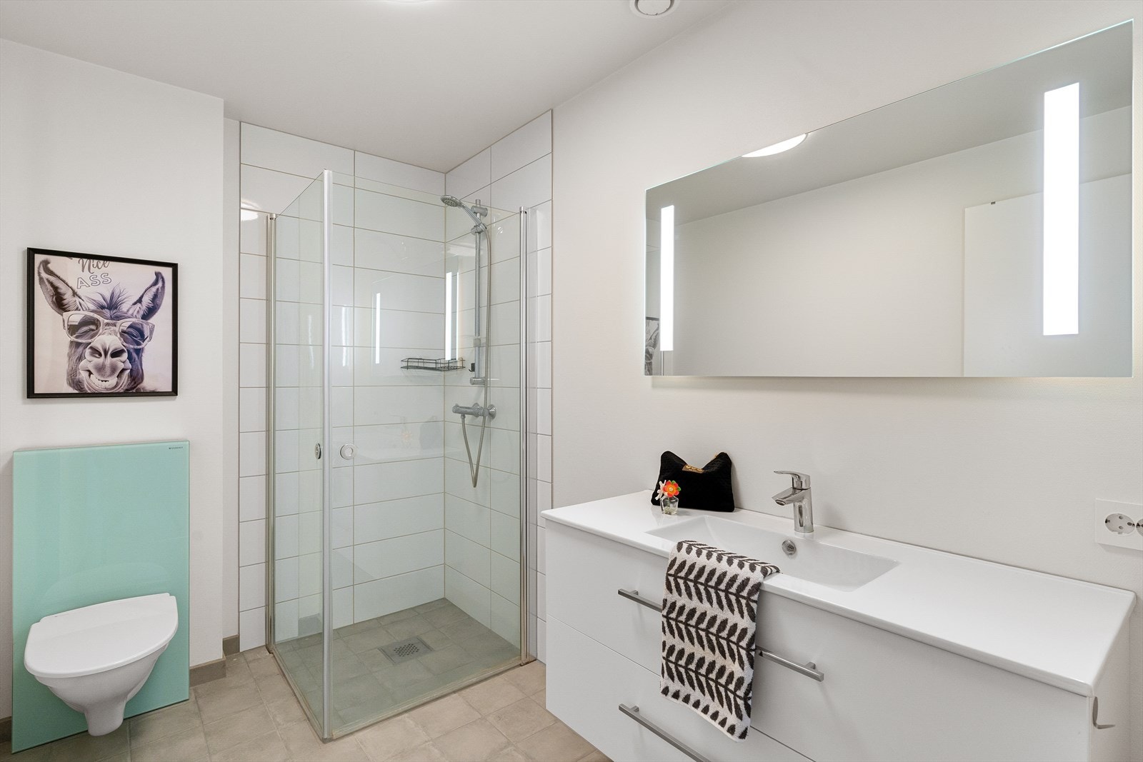 Flislagt badegulv og dusjnisje. Vask i skuffeseksjon, speil med integrert belysning. Galleribilde