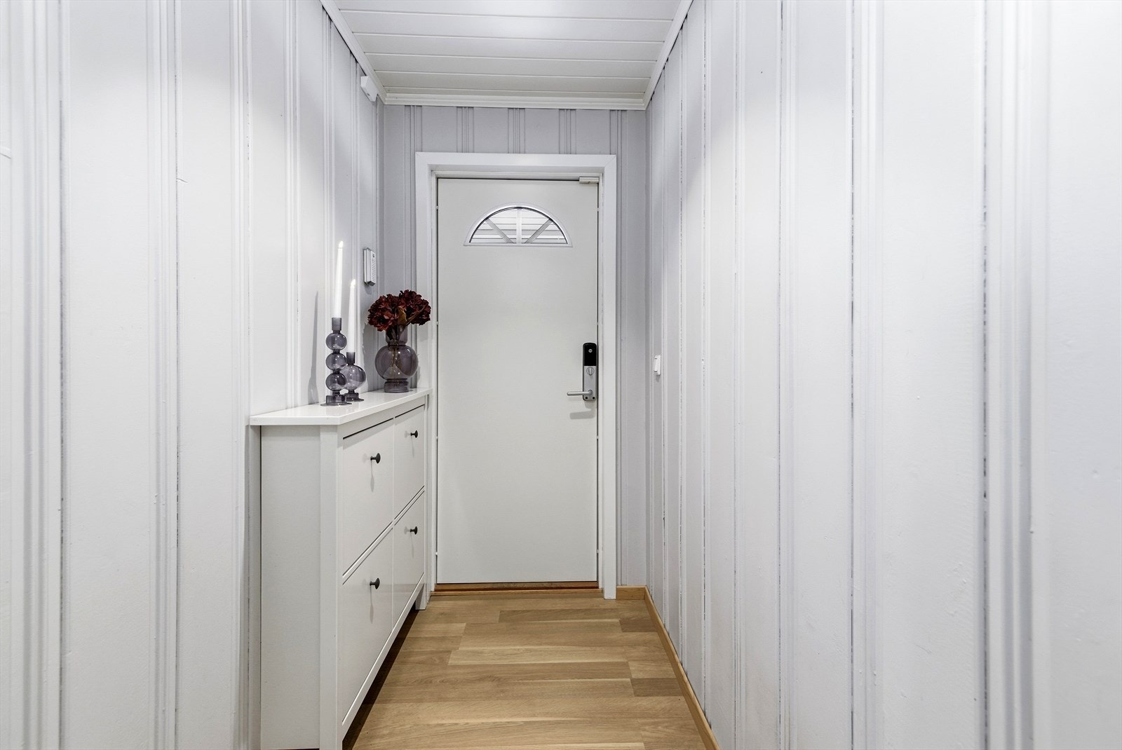 Lys og innbydende entré med panel på veggene. Galleribilde