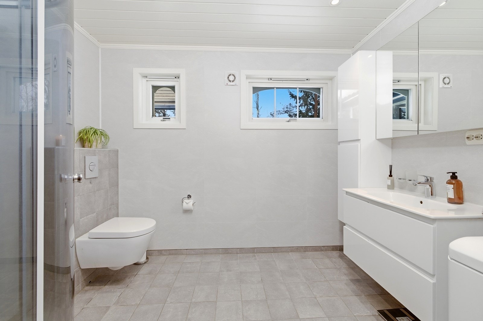 Her på badet er det flislagt gulv med elektriske varmekabler og stilrene baderomsplater på veggene. Galleribilde