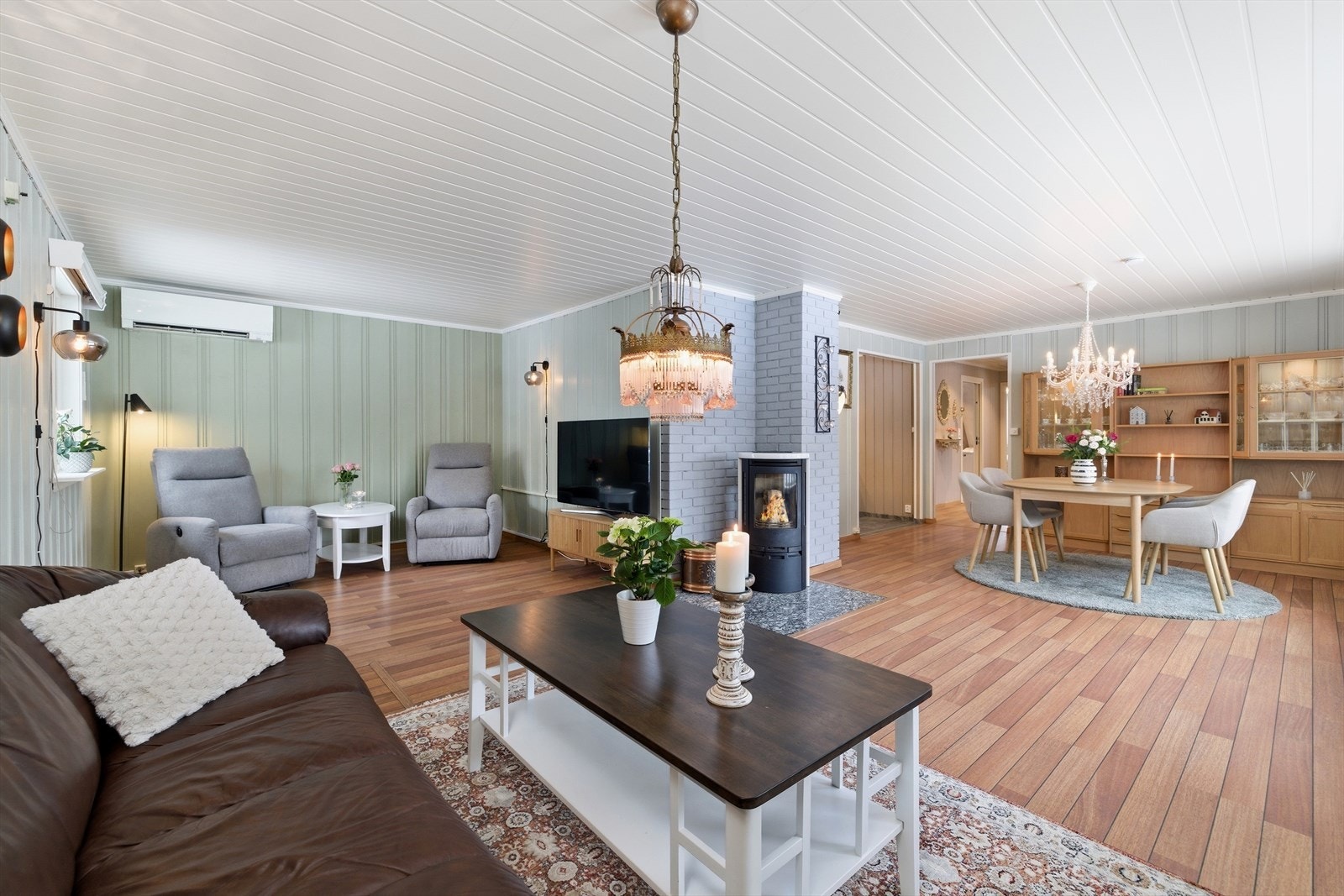 Romslig stue med overflater av parkett og laminat på gulv, og panel på vegger og i tak. Galleribilde