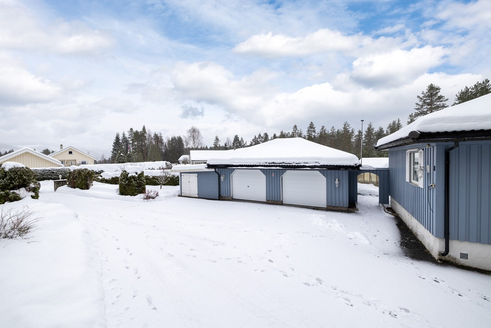 Stor, asfaltert gårdsplass med rikelig av parkeringsplass og to garasjer med nye porter fra 2023. Galleribilde