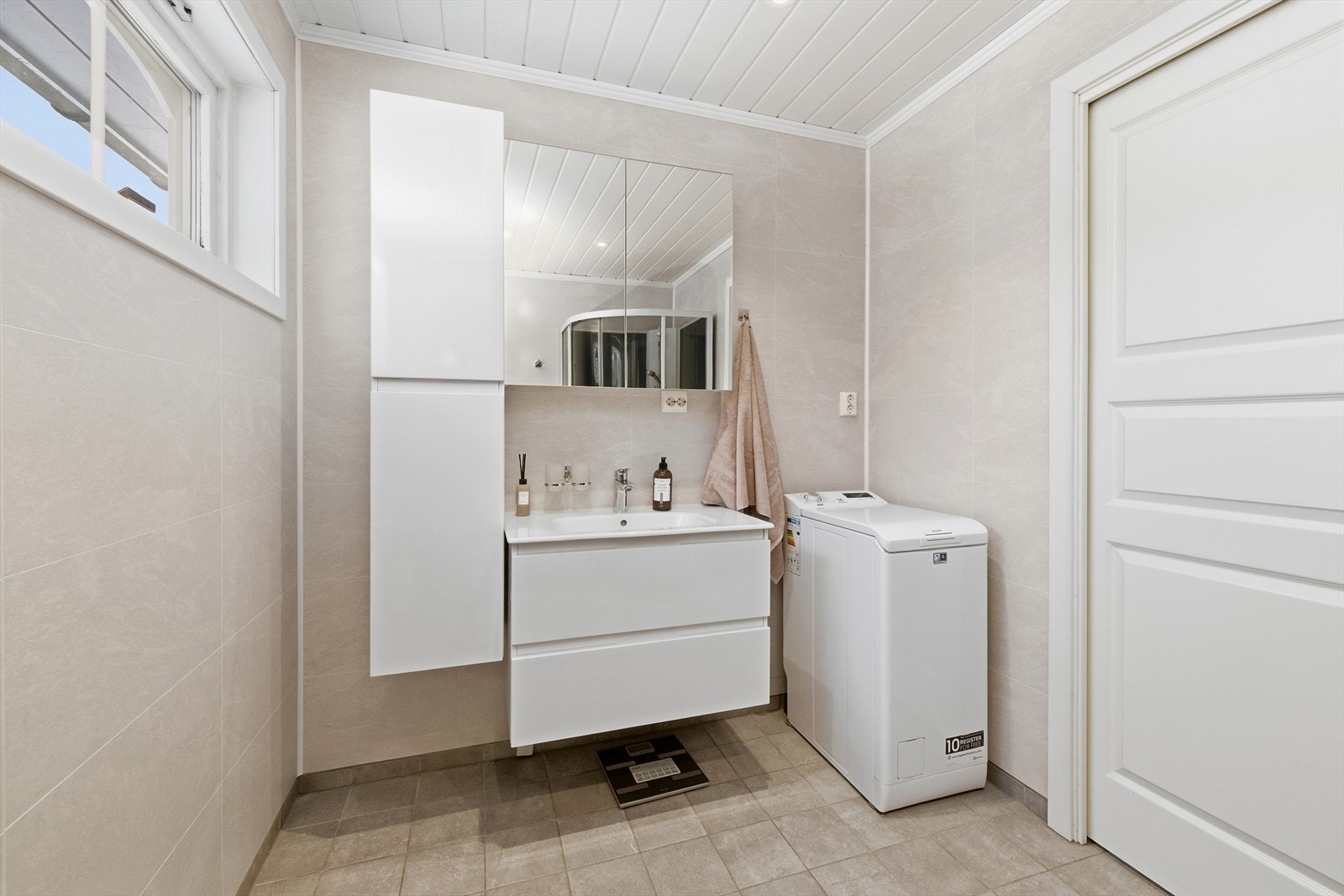 Moderne baderomsinnredning med nedfelt servant og praktisk opplegg for vaskemaskin. Galleribilde