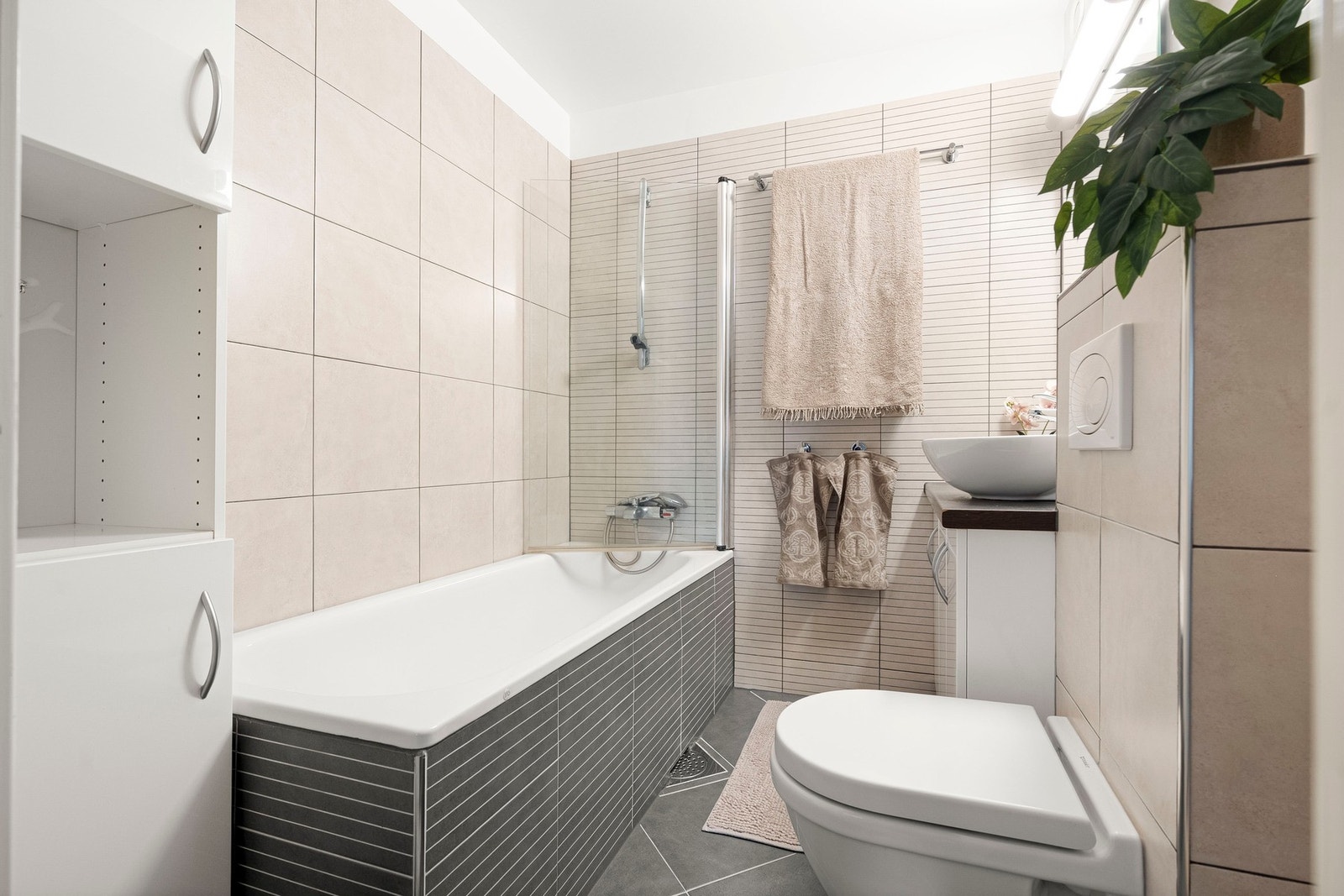 Et praktisk og stilrent, flislagt bad med behagelige varmekabler i gulvet. Galleribilde