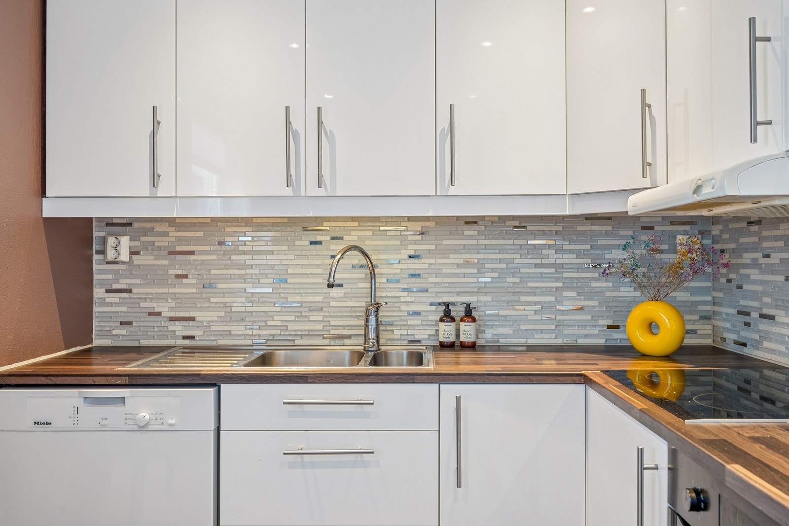 Den flislagte veggen over benkeplaten gir både et elegant uttrykk og en funksjonell overflate i hverdagsbruk Galleribilde