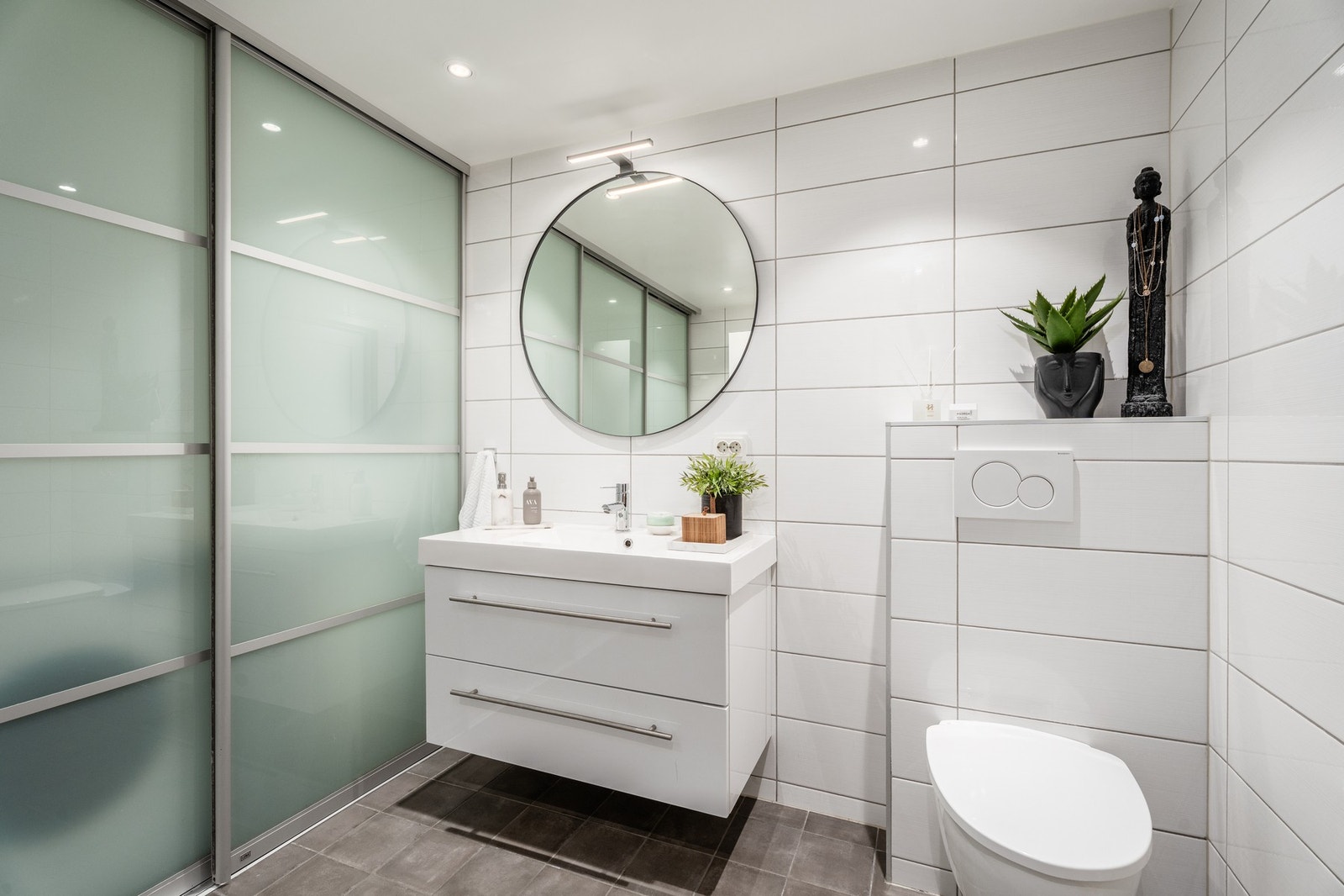 Servantinnredning med skuffer, veggfestet WC og ikke minst skyvedører med frostede fronter som skjuler vaskemaskin etc. Galleribilde