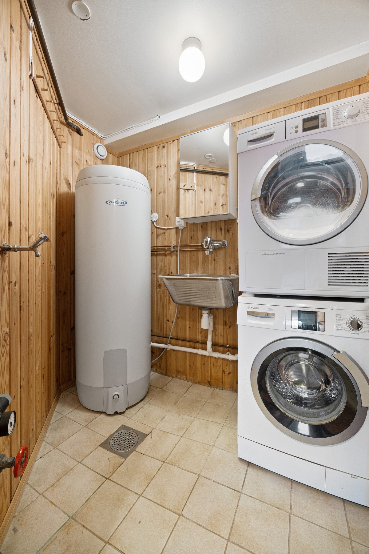 Flislagt vaskerom med god plass til vaskemaskin, tørketrommel og tørkestativ Galleribilde