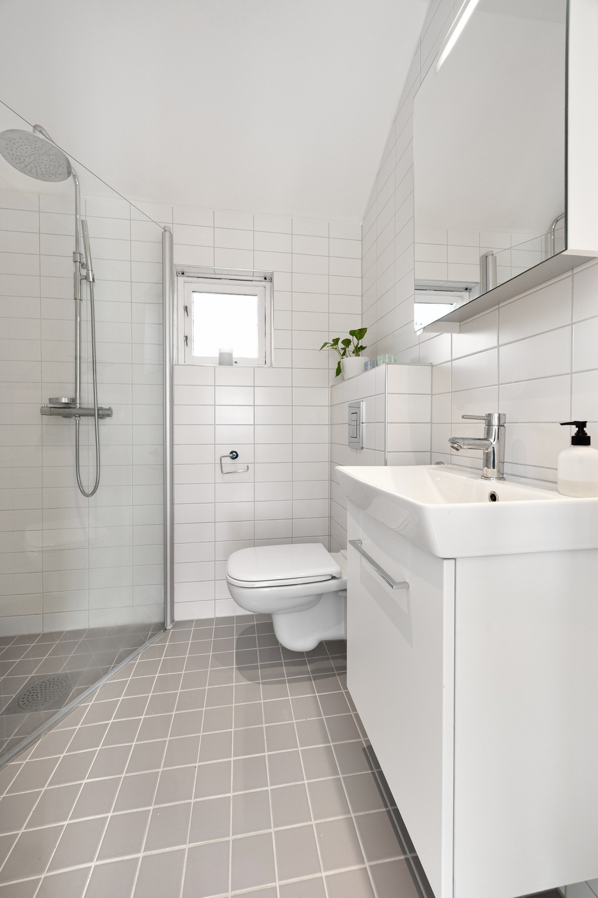 Ved siden av trappen i andre etasje finner du et innbydende og tidløst baderom med flislagt gulv og vegger Galleribilde