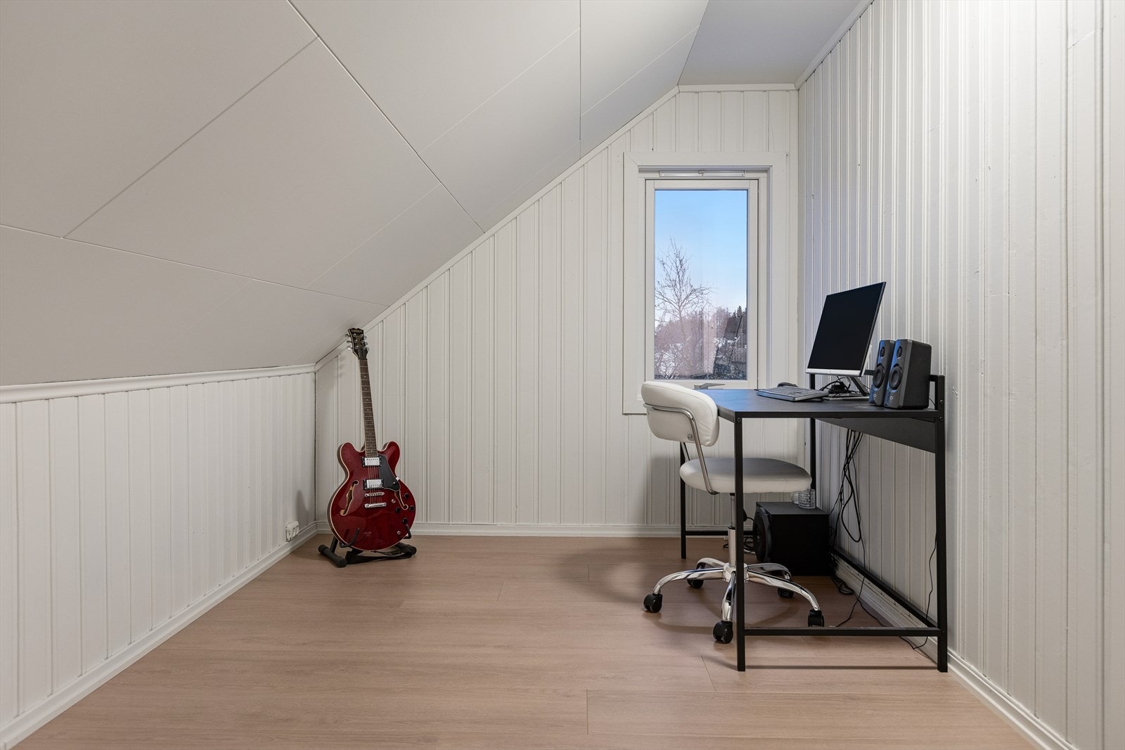 Skråtak med panelvegger gir rommet en koselig karakter, mens vinduet gir naturlig lysinnslipp. Galleribilde
