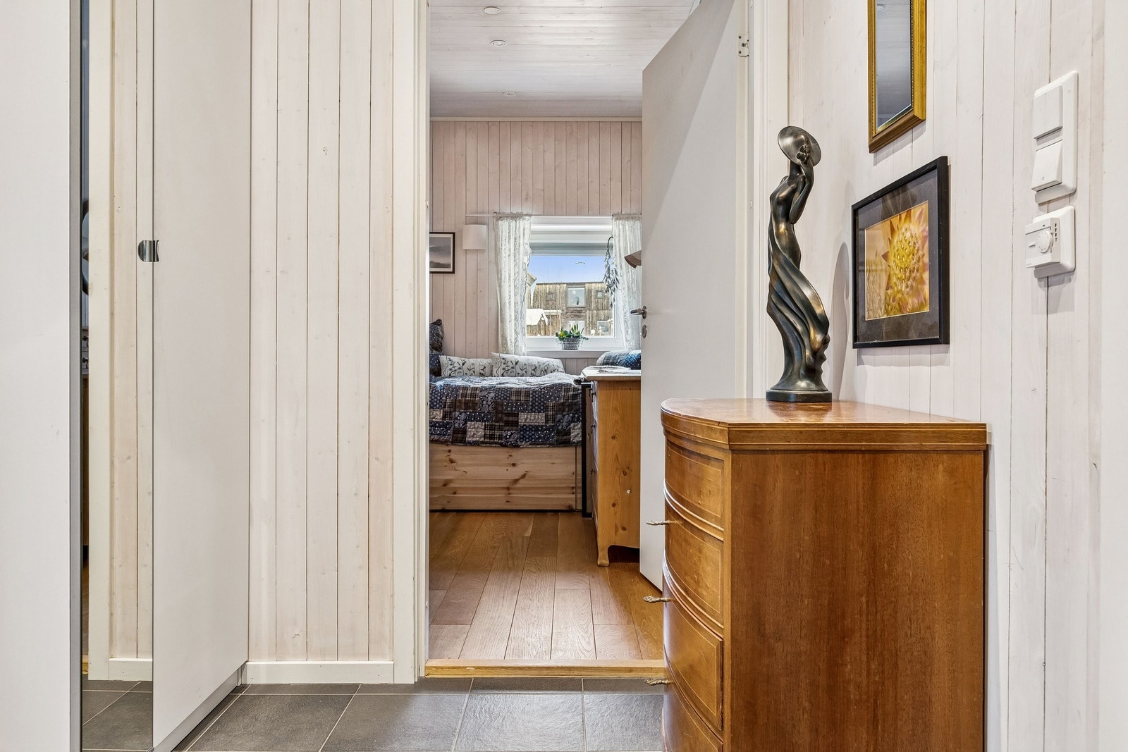 Om du snur deg, så ser du inn på soverommet. Du skimter senga der inne og ser at den en ralativt høy. Den har en stor oppbevaringsskuff. Galleribilde