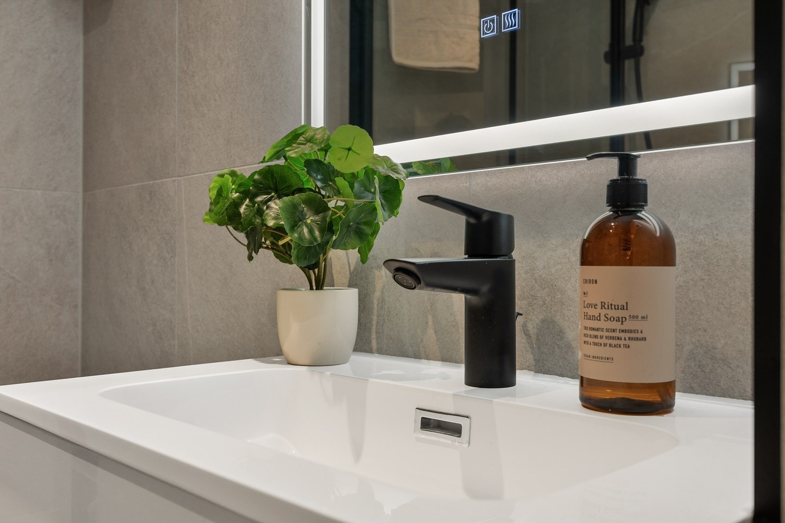 Tilbake på badet ser vi den formstøpte servanten med skuffeinnredning og speil med belysning. Galleribilde