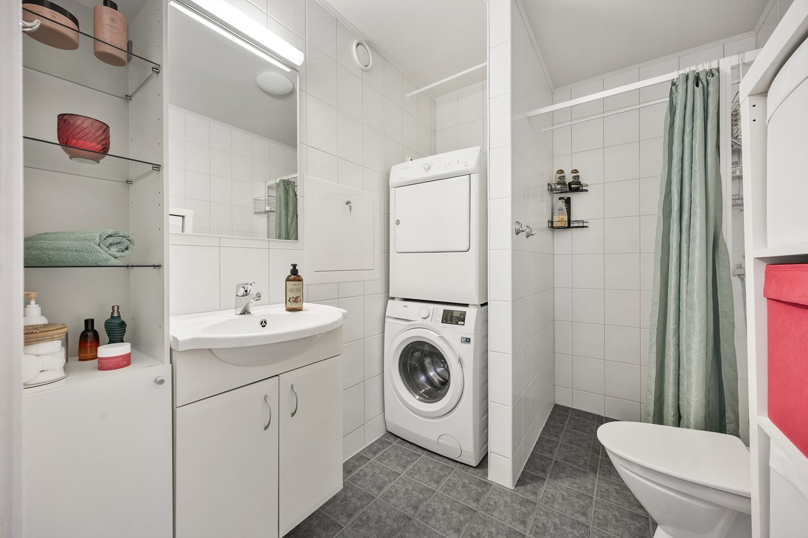 Det helflisede badet har en praktisk planløsning med egen nisje for vaskemaskin/tørketrommel . Galleribilde