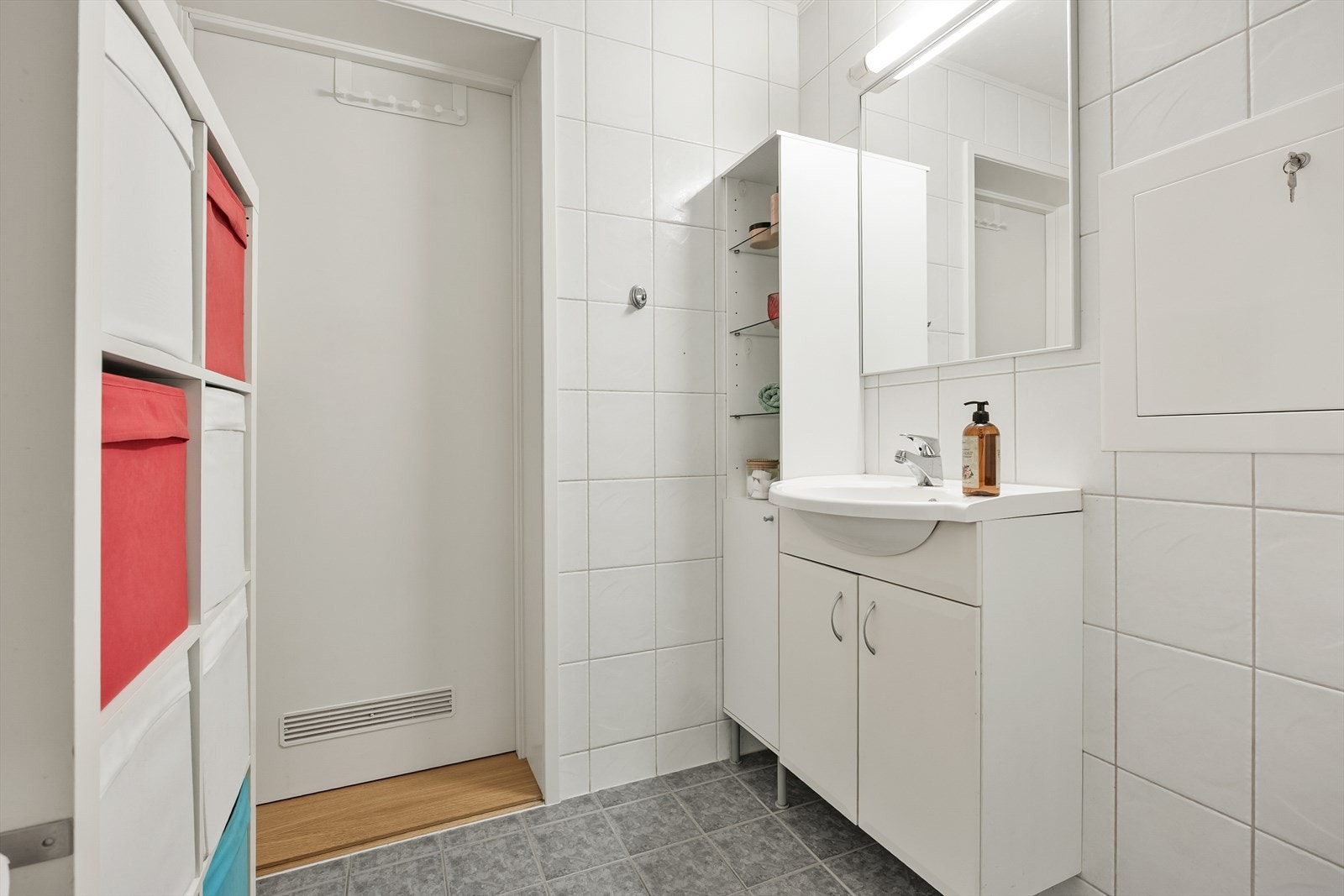 Innredningen består av servant over hvit skapseksjon, høyskap og stort speil med belysning. Galleribilde