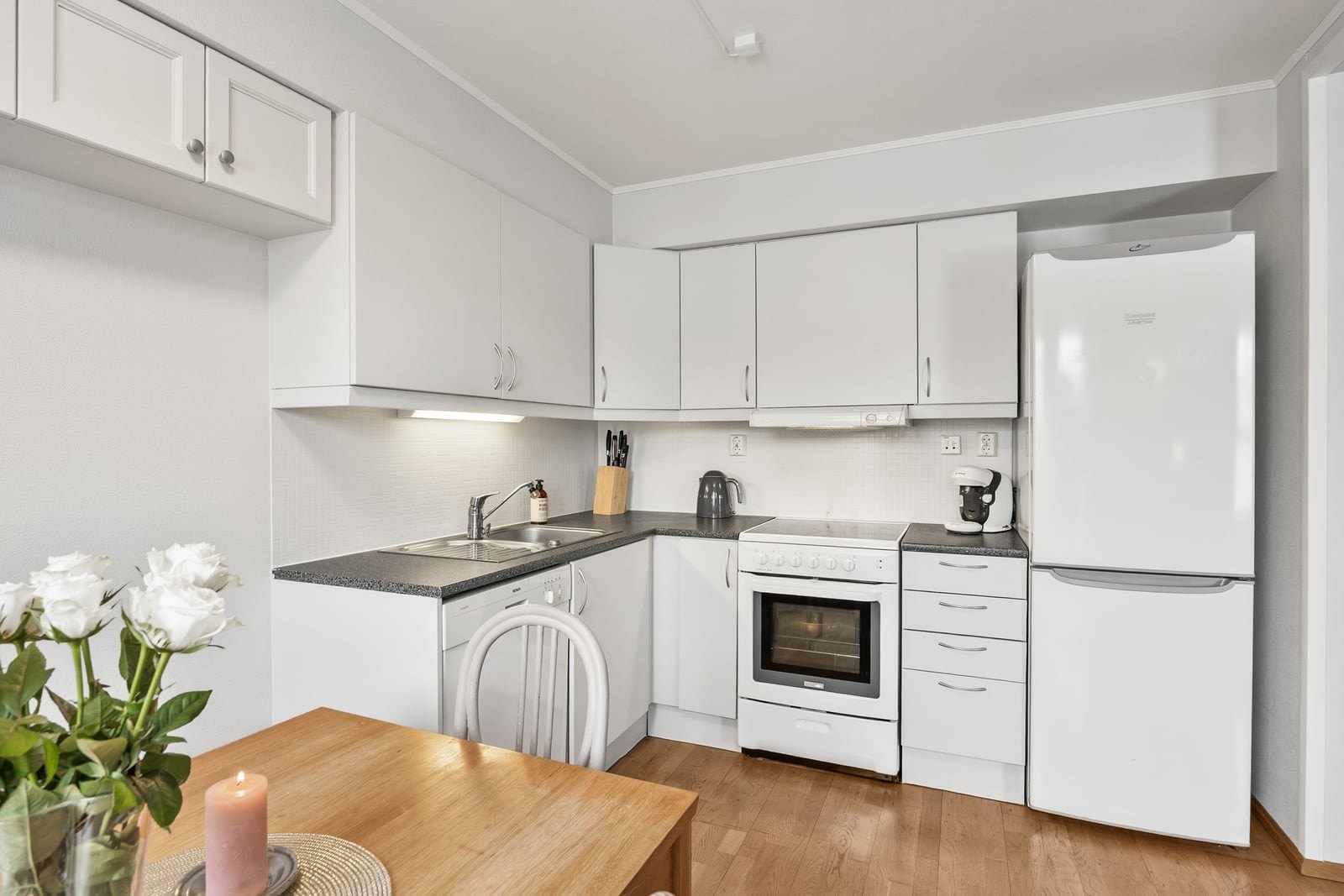 Innredningen har hvite, glatte fronter og koksgrå laminatbenkeplate med nedfelt oppvaskkum. Galleribilde