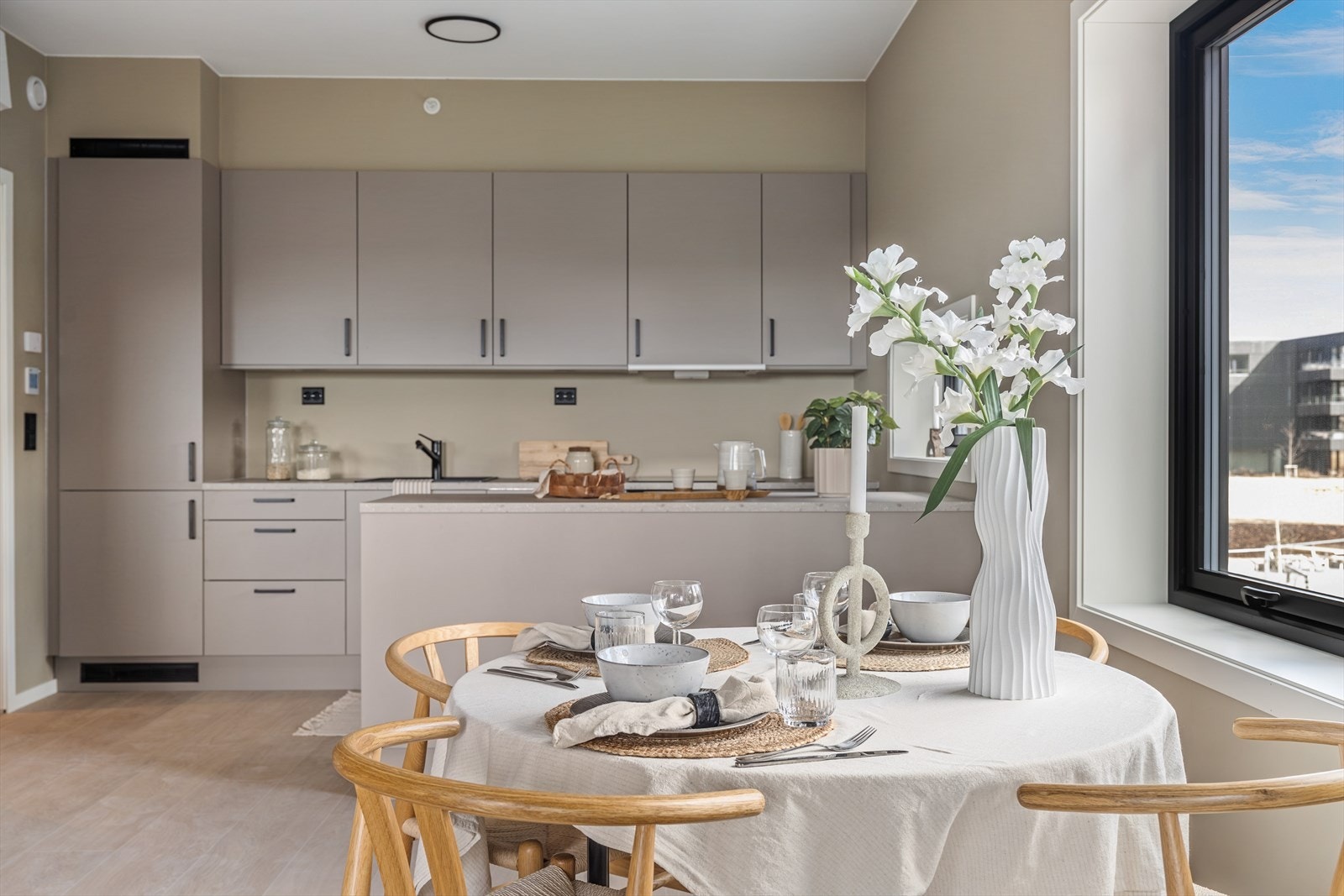 Kjøkkenet er stilrent innredet med beige, slette fronter og benkeplate i laminat. Sorte detaljer er gjennomgående og gir et moderne og stramt uttrykk. Galleribilde