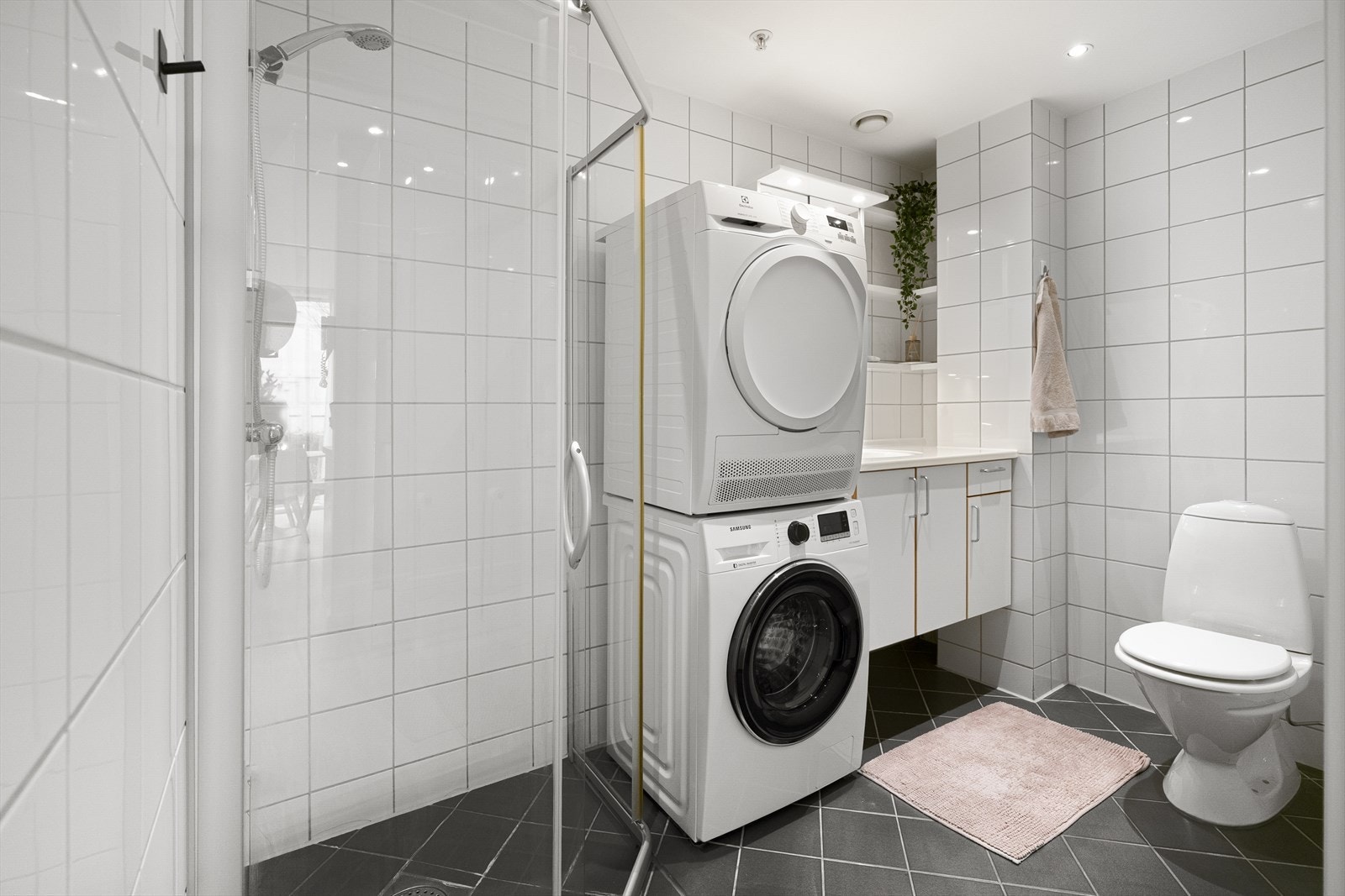 Baderommet fremstår tidløst og delikat, helfliset med lyse veggfliser som harmonerer fint med mørkere gulvfliser. Galleribilde