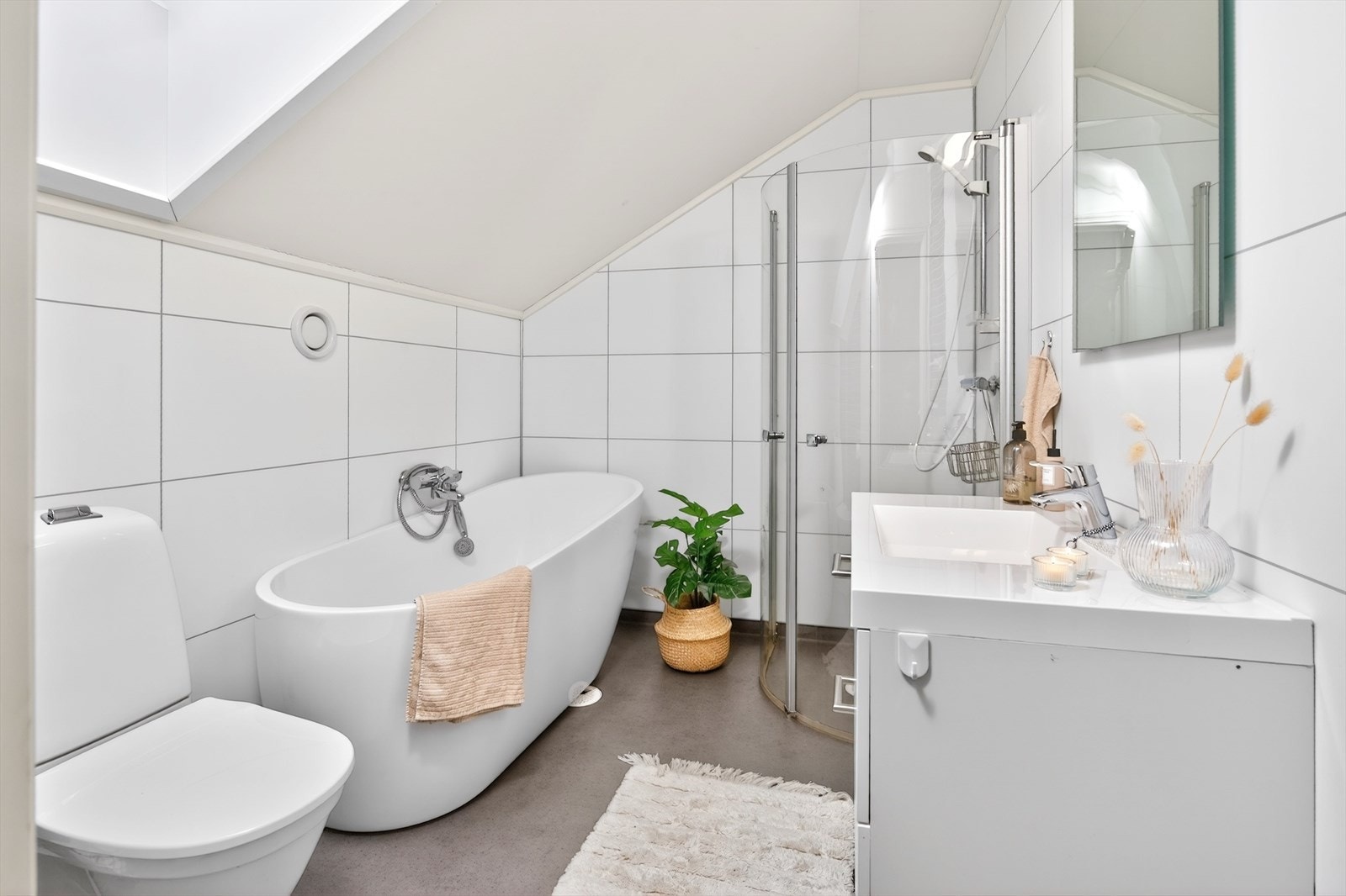 Delikat bad med badekar, heldekkende servant med innredning, wc og dusjhjørne. Galleribilde