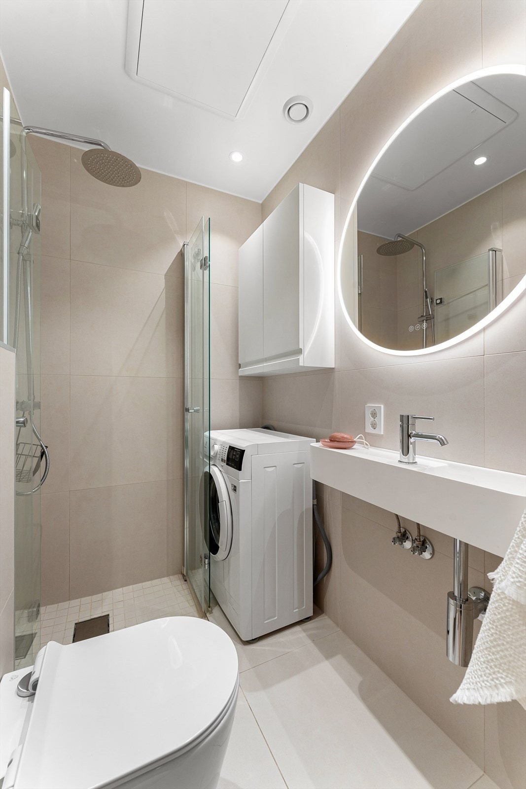 Badet er innredet med dusjhjørne med innfellbare dører i herdet glass, servant og veggfestet toalett med innebygget sisterne. I tillegg er det praktisk opplegg for vaskemaskin. Galleribilde