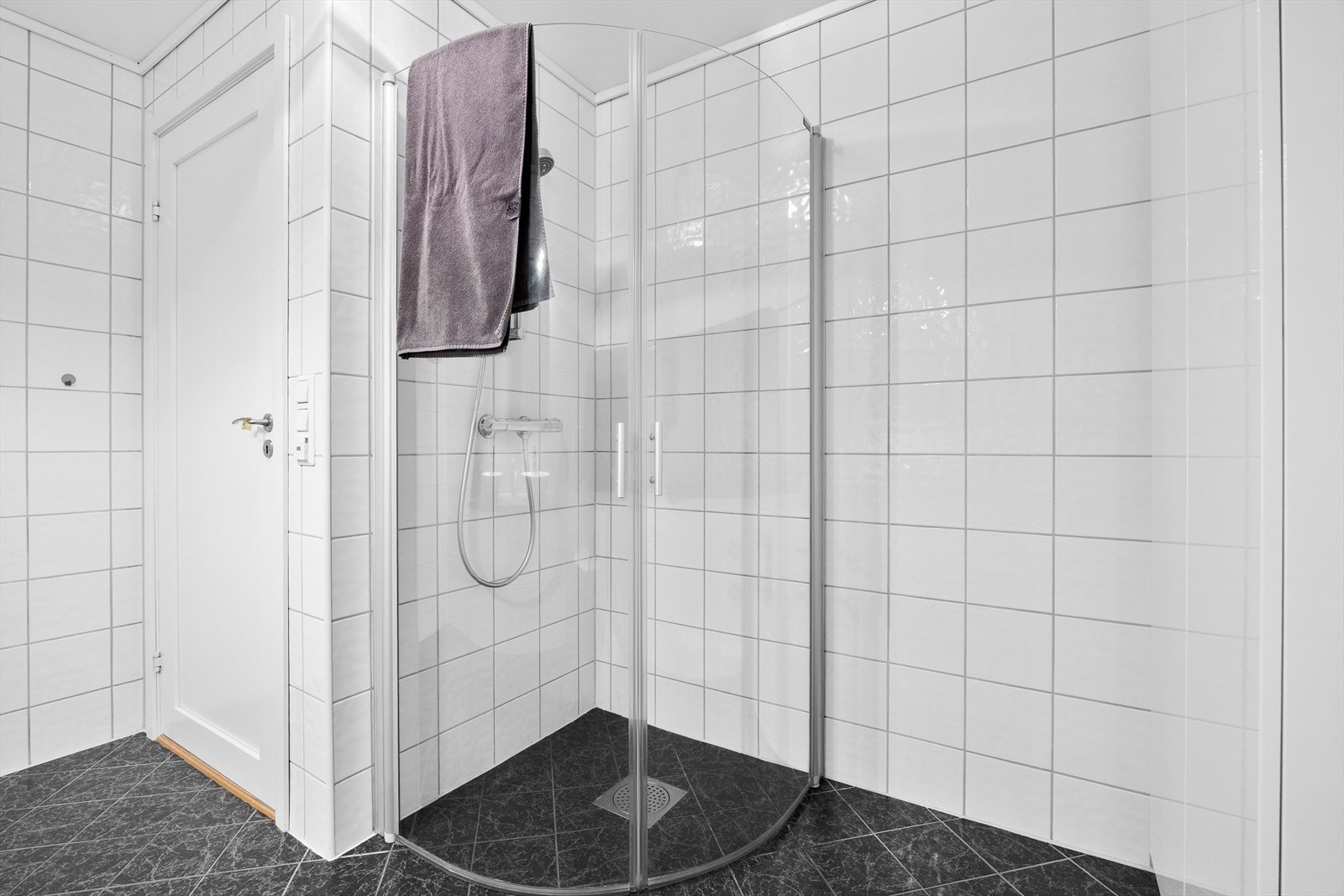 Badet er utstyrt med veggtoalett, dusjhjørne med glassdører, høyskap og baderomsinnredning med dobbel servant, speil og belysning. Galleribilde