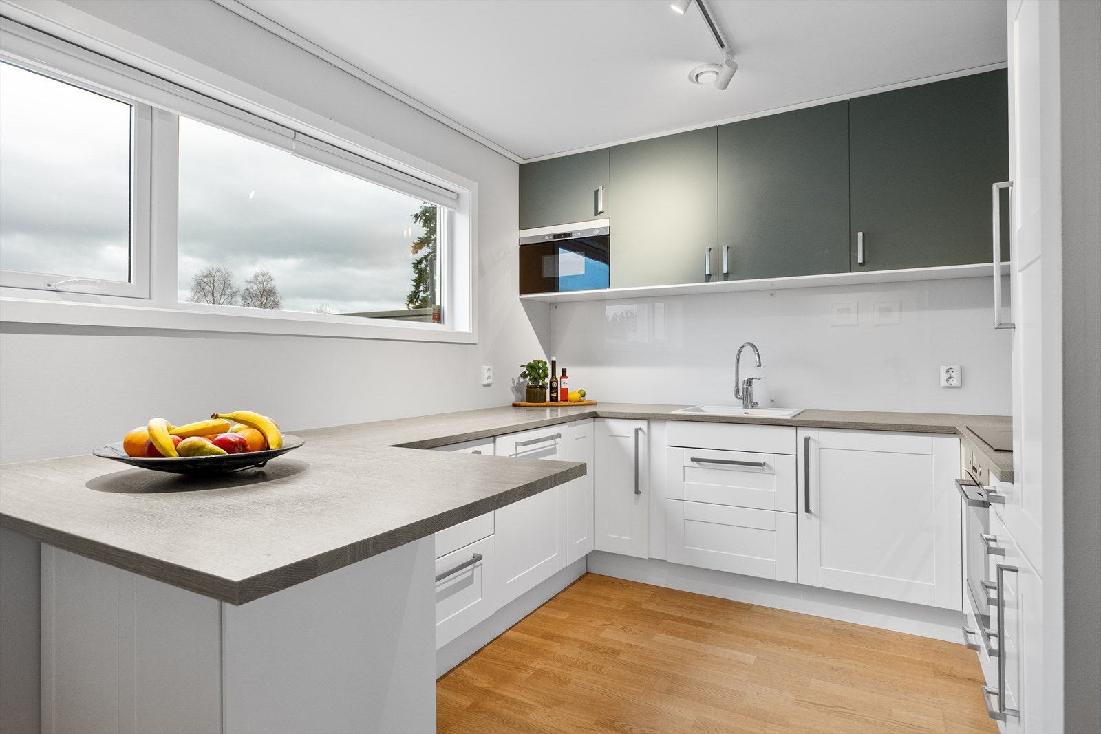 Kjøkkenet har en flott innredning fra Ikea med hvite profilerte fronter nede og med glatte grønne fronter på overskapene. Galleribilde