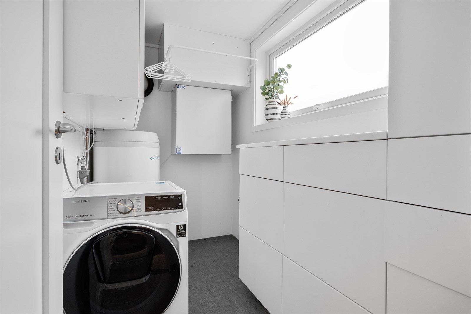 Innenfor kjøkkenet finner man et teknisk rom/vaskerom med belegg på gulv og malte veggflater. Galleribilde