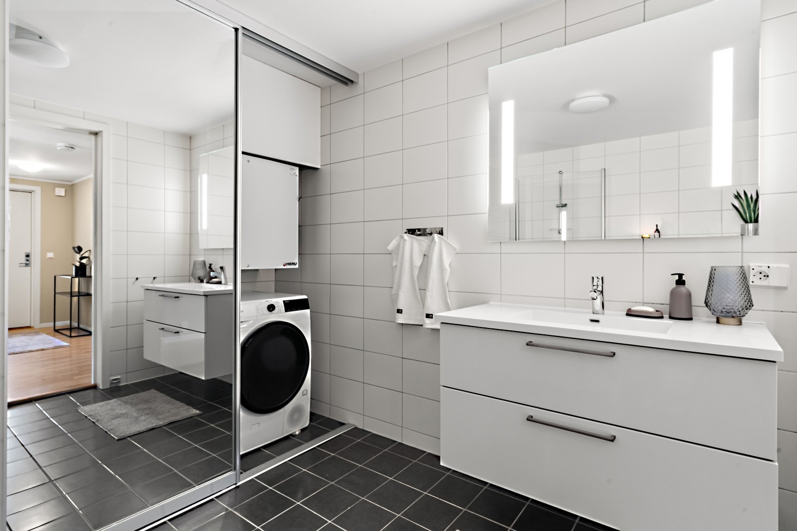 Badet har smart skyvedør i speil som skjuler vaskemaskinen Galleribilde