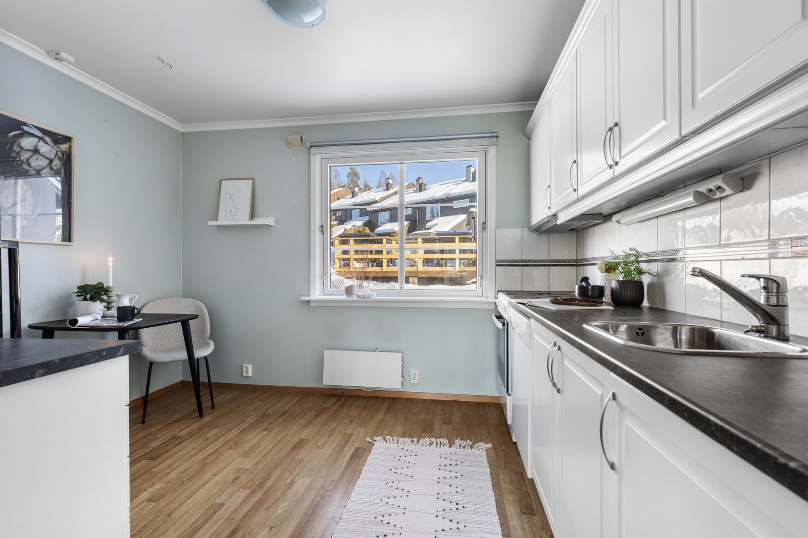 Kjøkkeninnredningen er fra 2009 og har et klassisk uttrykk med hvite, profilerte fronter og mørk laminatbenkeplate med nedfelt stålkum. Galleribilde