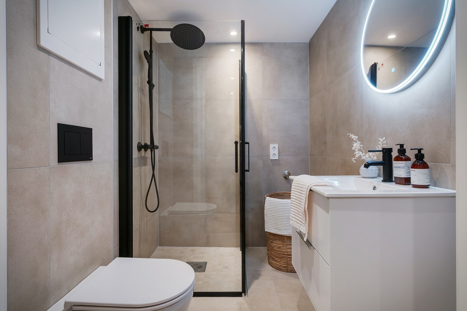 Badet er helfliset og er innredet med nedfelt servant, veggmontert toalett, dusjvegger og opplegg for vaskemaskin. Galleribilde