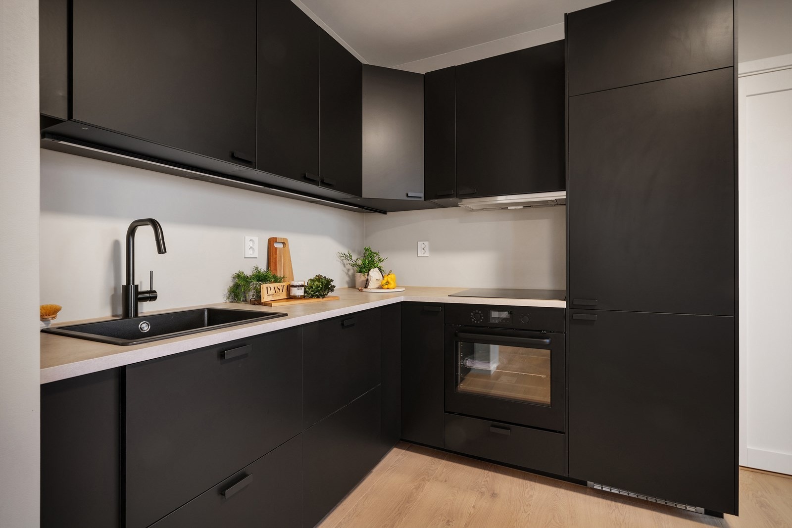 Kjøkkenet, fra IKEA, er lokalisert i midten av rommet og er innredet med mørke glatte fronter. Galleribilde