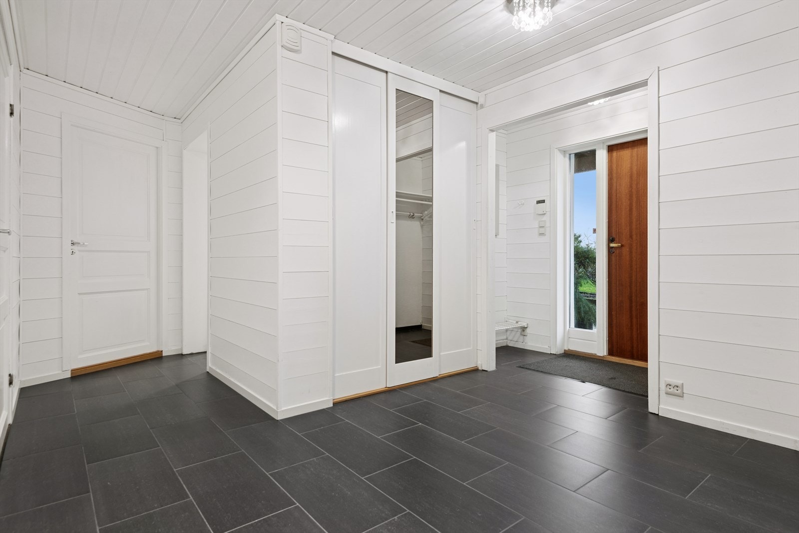 Stor og romslig inngang med fliser på gulvet og god plass til yttertøy og sko. Galleribilde
