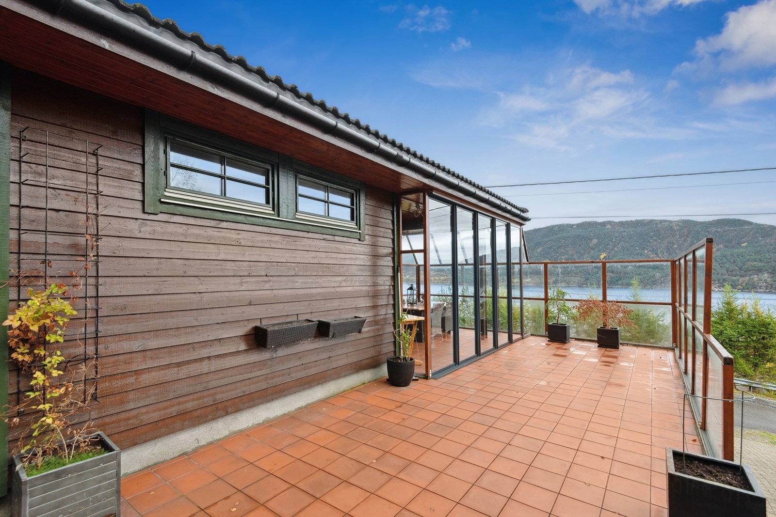 Fra den romslige terrassen nyter du vakker utsikt mot fjorden, omgitt av fredelige omgivelser. Her er det god plass til hagemøbler, perfekt for avslappende stunder, måltider i det fri eller hyggelige samlinger med familie og venner. Galleribilde