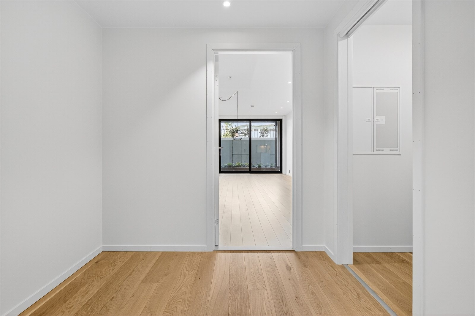 Parkettgulv og slettmalte vegger gir et rent uttrykk i gangen. Galleribilde