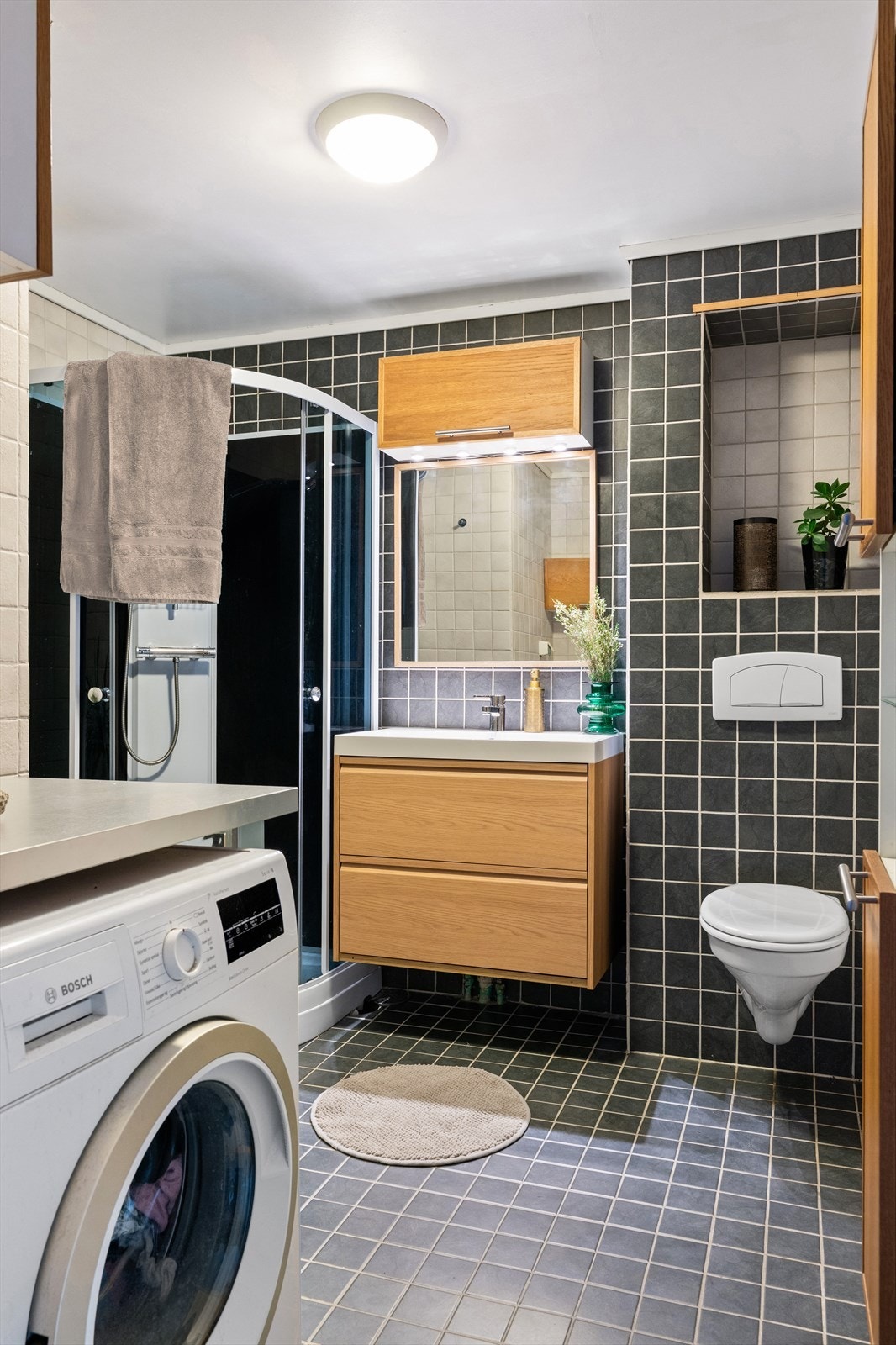 Badet har et flislagt gulv med varmekabler og opplegg for vaksemaskin. Galleribilde