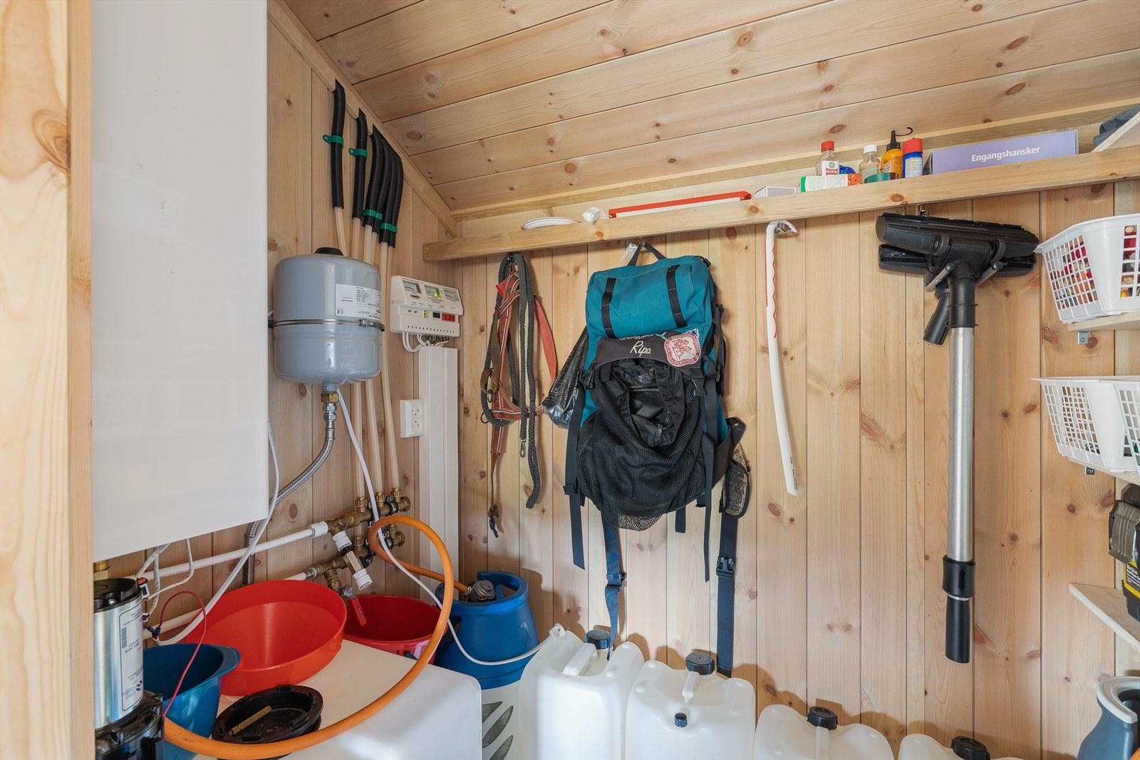 I innvendig bod/teknisk rom finner du propandrevet vannvarmer som henter vann fra sisterne som fylles manuelt. Her er også hyller for praktisk oppbevaring. Galleribilde