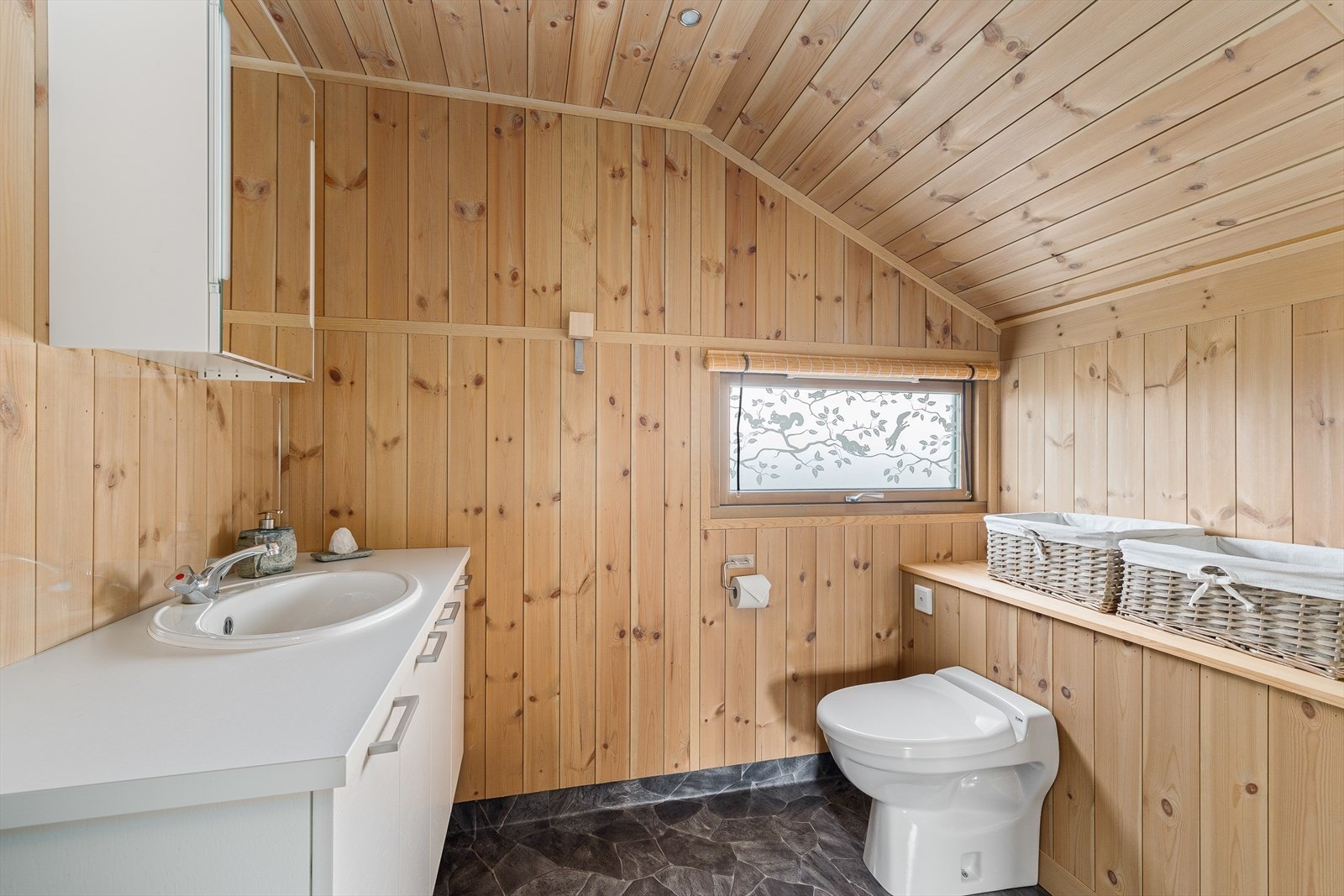 Her er det innredning med glatte, malte fronter og nedfelt servant, speilskap på vegg samt vakuumtoalett av typen Jetz. Galleribilde