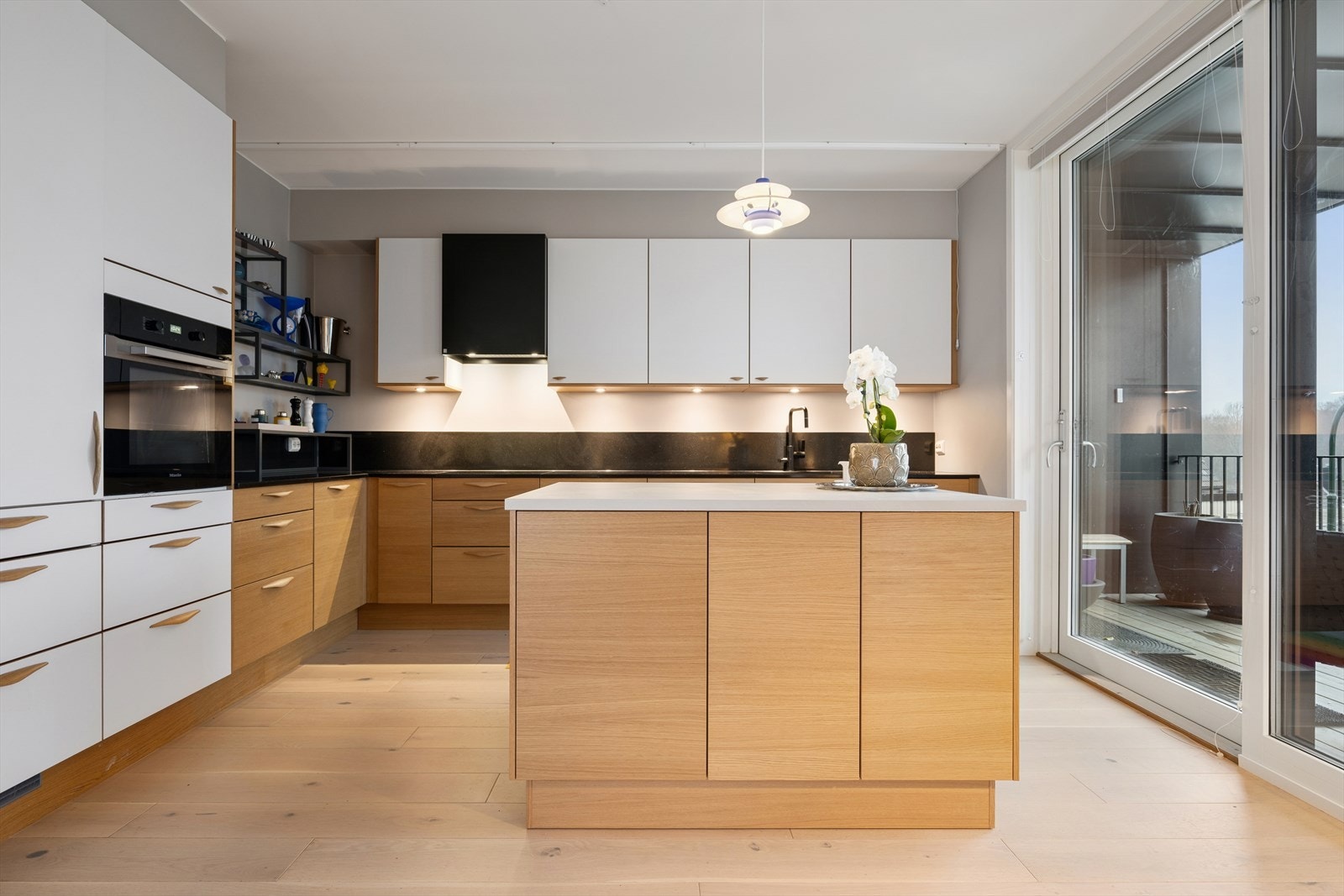 Kjøkken med flyttbar kjøkkenøy på hjul, integrerte hvitevarer og benkeplate i en kombinasjon av laminat og stein. Galleribilde