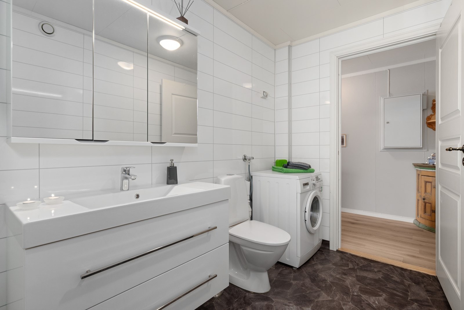 Badet har dusjkabinett, wc, servant med skapplass samt opplegg for vaskemaskin. Galleribilde