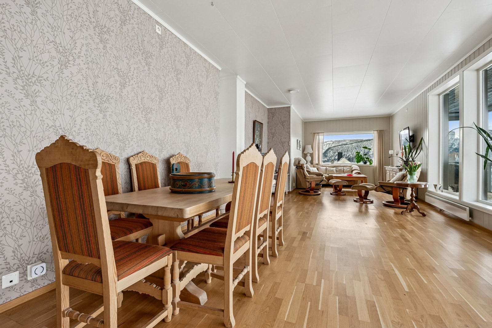 Lys og romslig stue med store vinduer som gir naturlig lysinnslipp og utsikt mot naturen. Vinduene i glassverandaen skjermer for trafikk-støy. Galleribilde