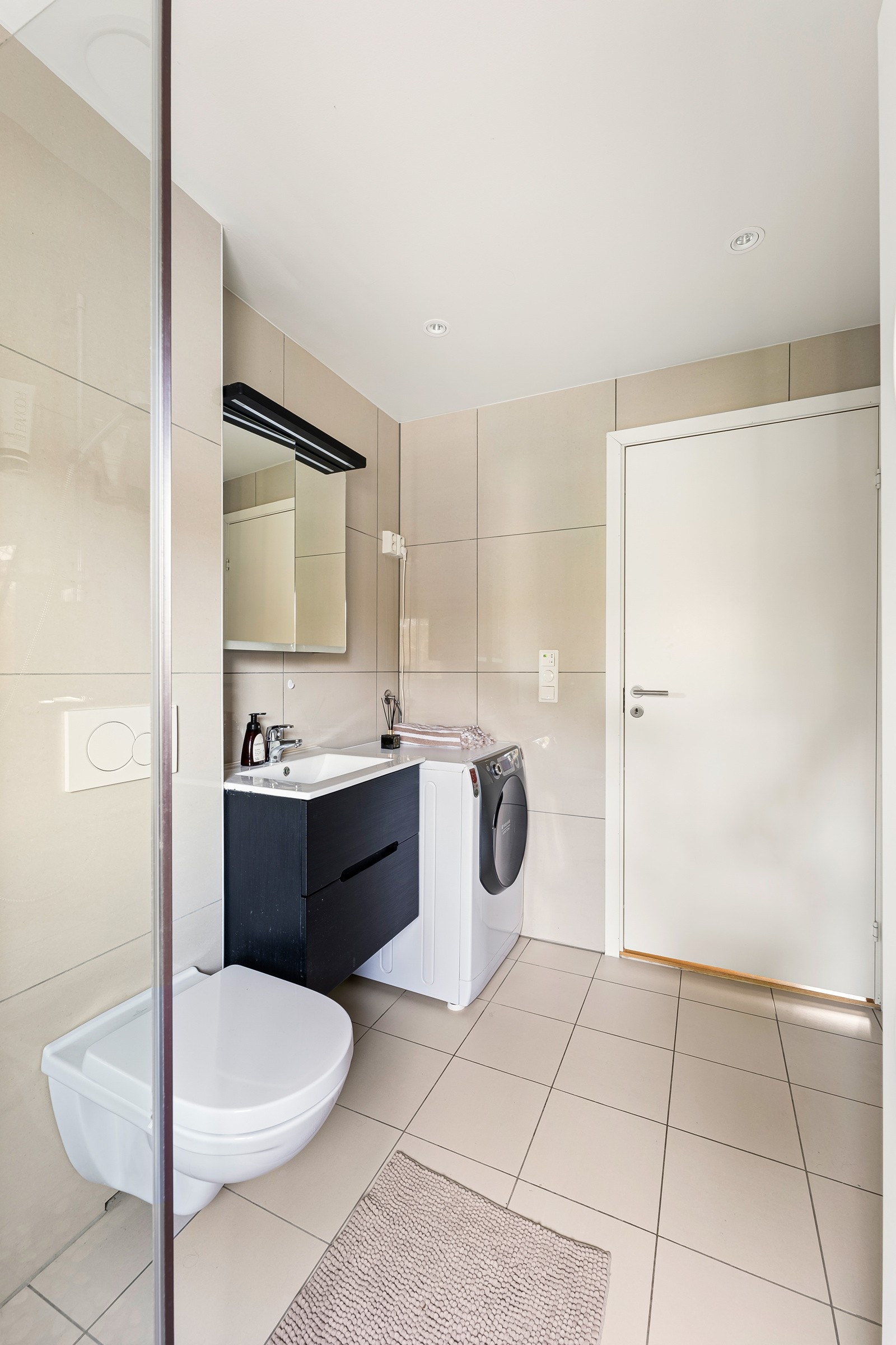 Her finner du dusjhjørne, servant, opplegg for vaskemaskin og et vegghengt toalett. Galleribilde