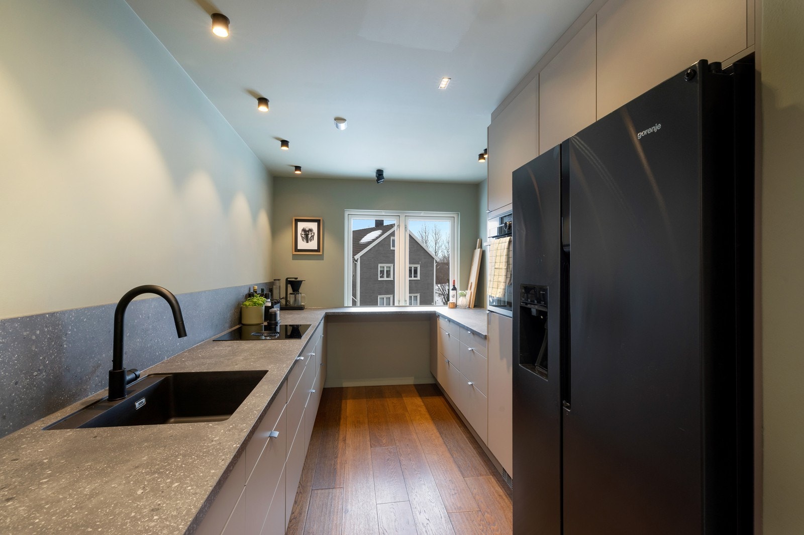 Et lekkert kjøkken med mye skap- og benkeplass. Integrert platetopp med ventilator, kjøl/frys, oppvaskmaskin og stekeovn. Benkeplate i kompositt med nedfelt servant Galleribilde