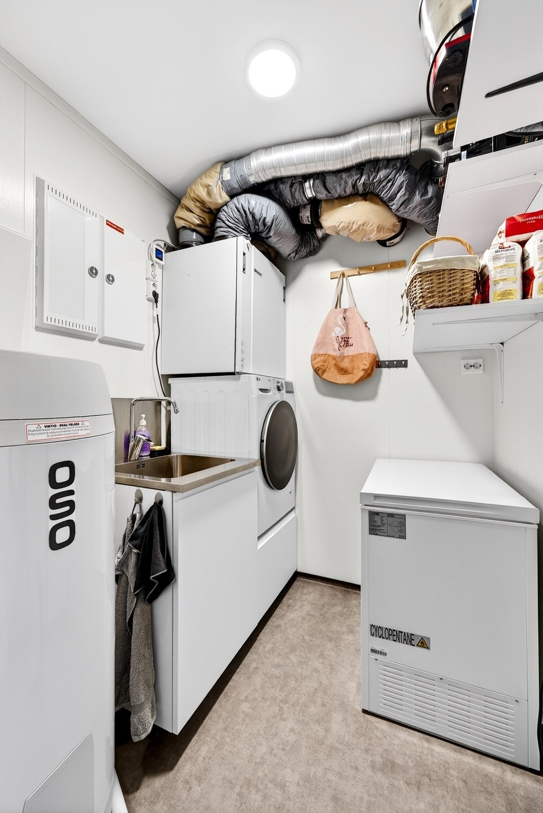 Funksjonelt vaskerom med utslagsvask og forhøyet løsning til vaskemaskin, samt plass til frysboks. Galleribilde