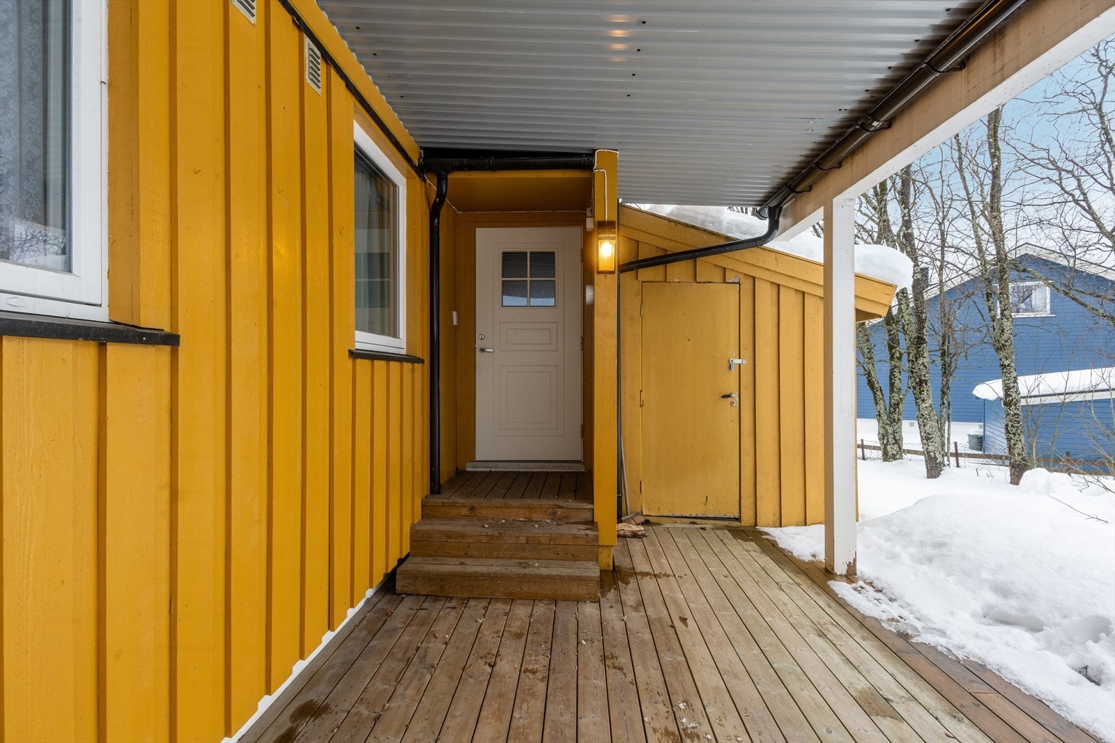 Overbygget inngangsparti med markterrasse og hoveddør med elektronisk kodelås. Galleribilde