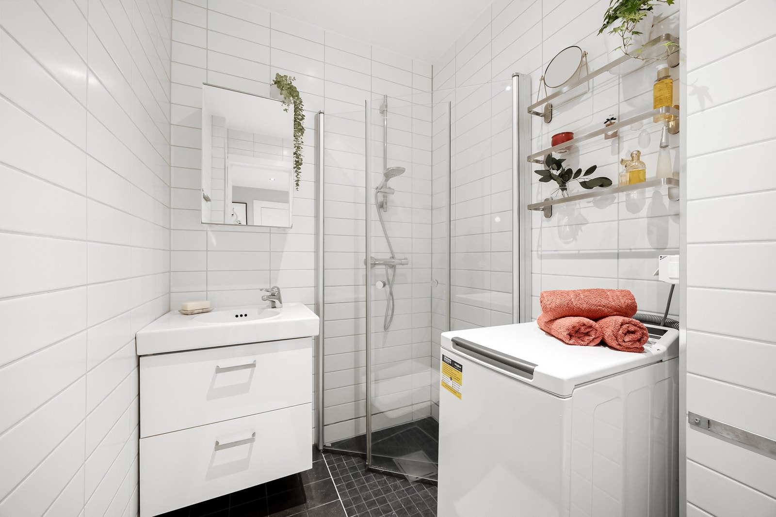 Flislagt og tidløst baderom fra 2012 med servantskap med heldekkende servant og speilskap over servant, samt dusjhjørne med svingdører og veggmontert toalett. Galleribilde